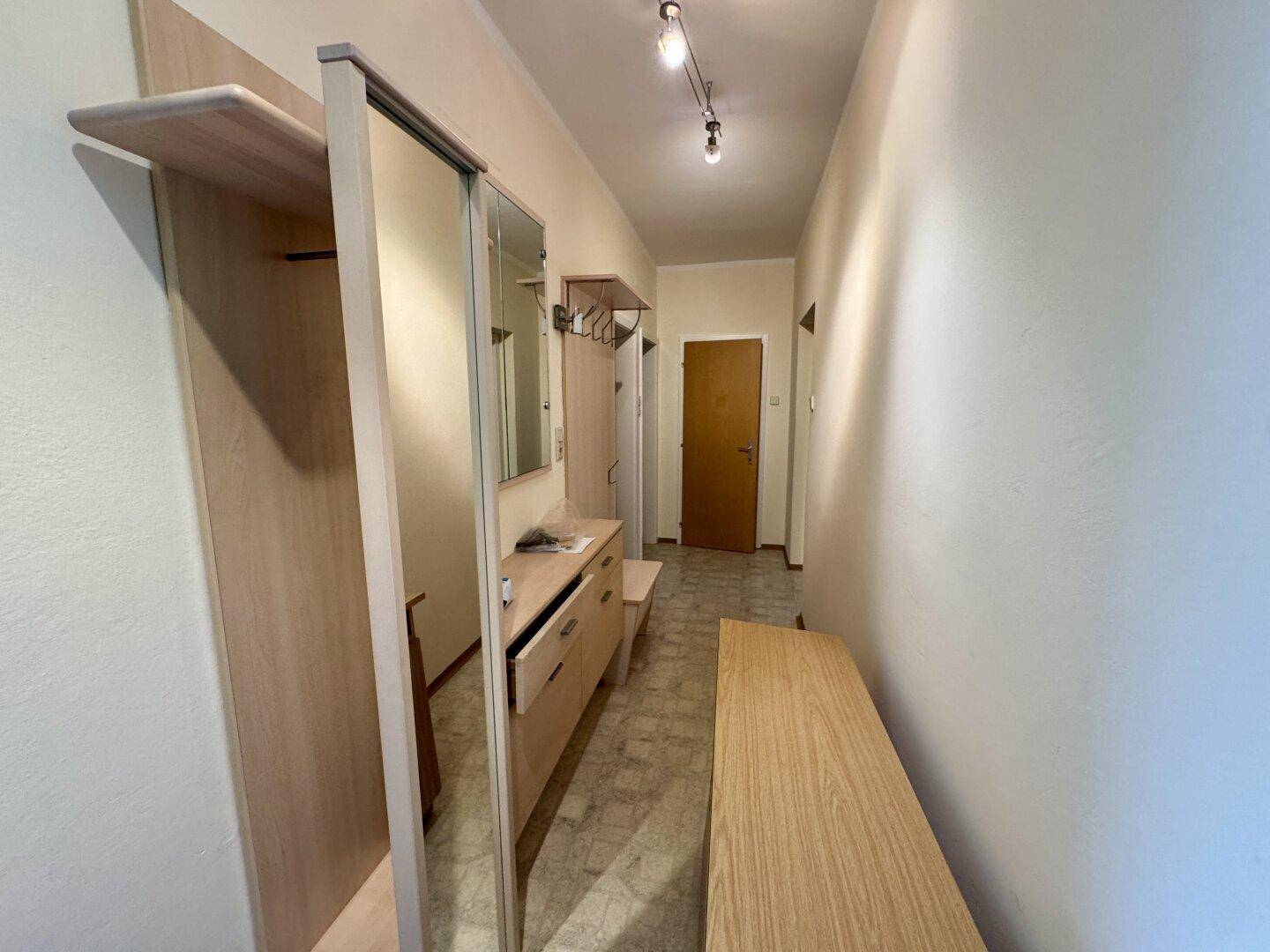 Heller Flur mit Garderobe, Spiegel und hellem Bodenbelag, einladend gestaltet.