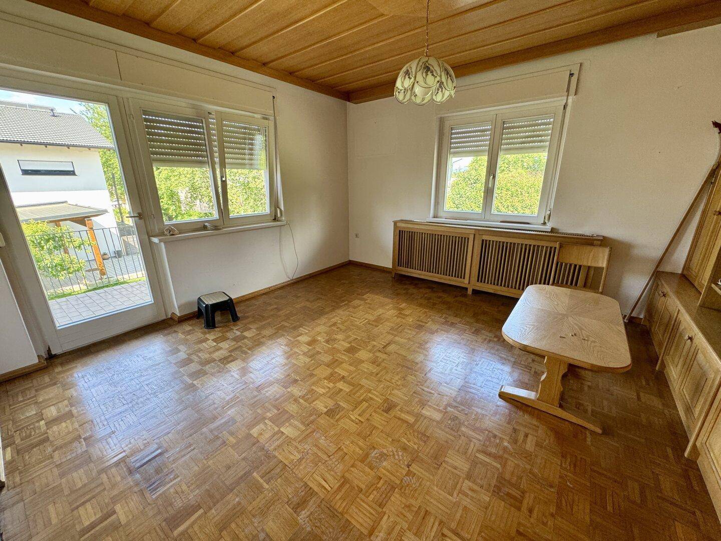 Wohnzimmer mit Holzdecke, Parkettboden und Zugang zum Balkon, hell und geräumig.