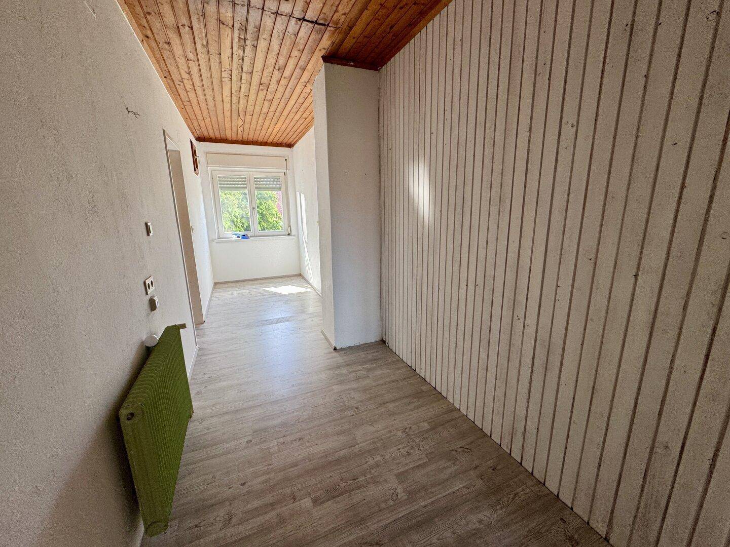 Flur mit Holzdecke, Laminatboden und vertäfelten Wänden.