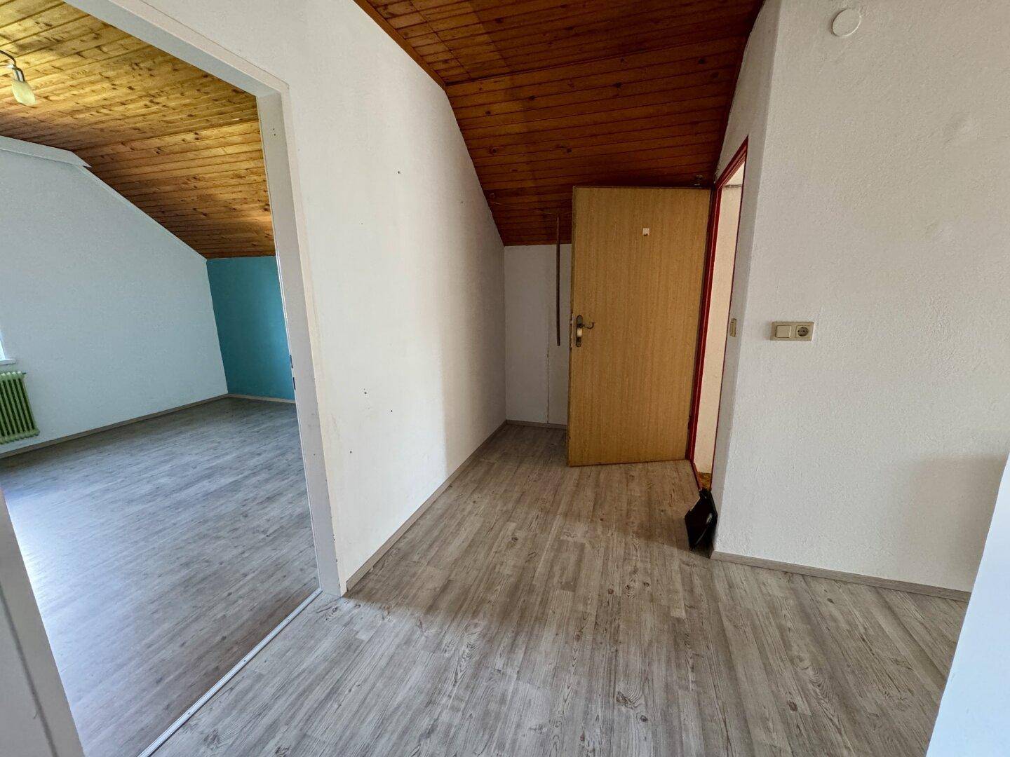 Flur im Dachgeschoss mit Holzbalkendecke und Laminatboden, führt zu weiteren Räumen.