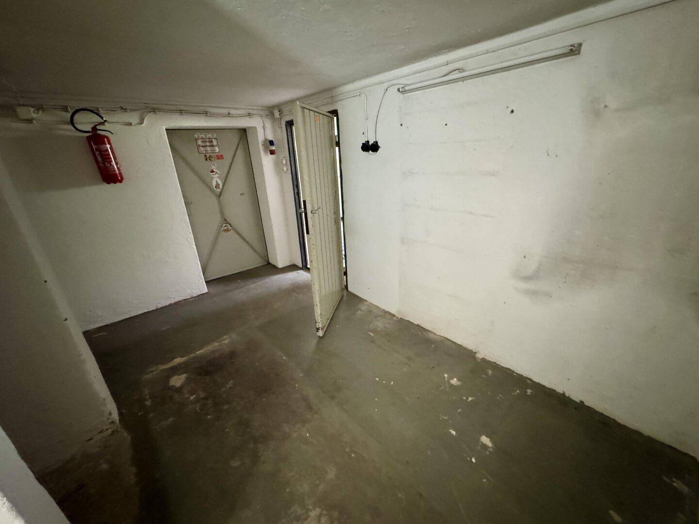 Kellerbereich mit Betonboden, weißen Wänden und zwei Türen.