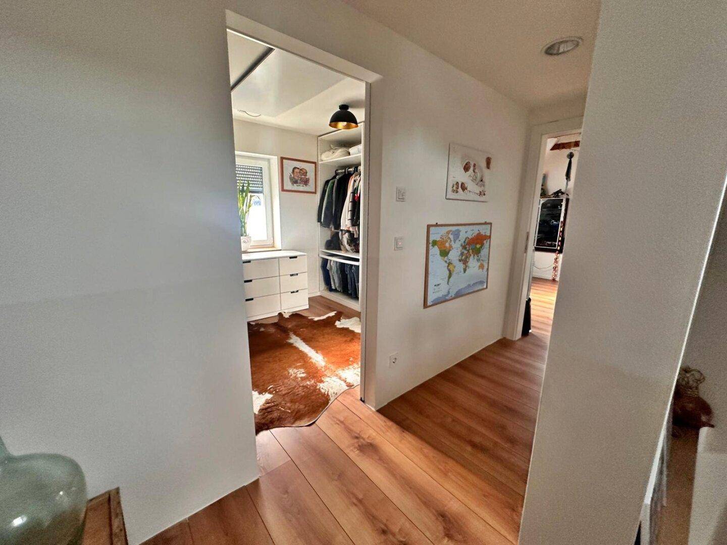 Heller Flur mit Holzboden, der zu einem begehbaren Kleiderschrank führt.