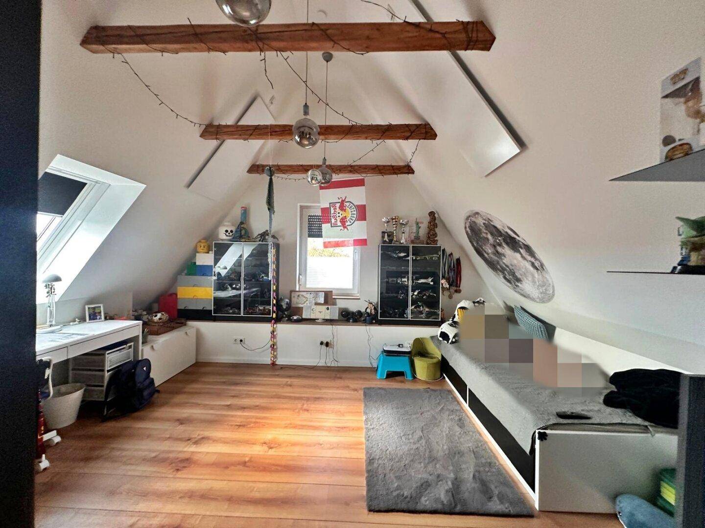 Kinderzimmer im Dachgeschoss mit Holzbalken, Dachschräge und Spielzeug.