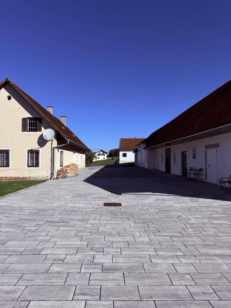 Gepflasterter Hofbereich zwischen traditionellen Gebäuden unter klarem blauem Himmel.