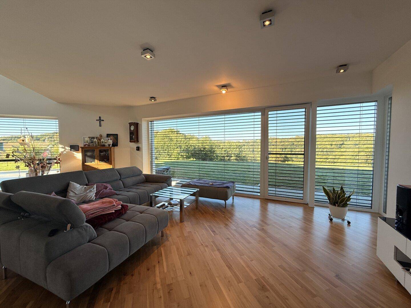 Gemütliches Wohnzimmer mit großem Sofa, Holzboden und weitem Ausblick durch die Fenster.