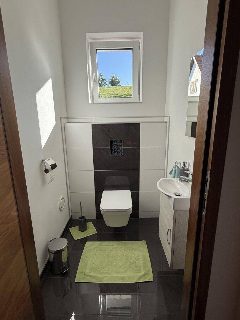 Helles Gäste-WC mit Fenster, wandhängendem WC und modernem Waschbecken.