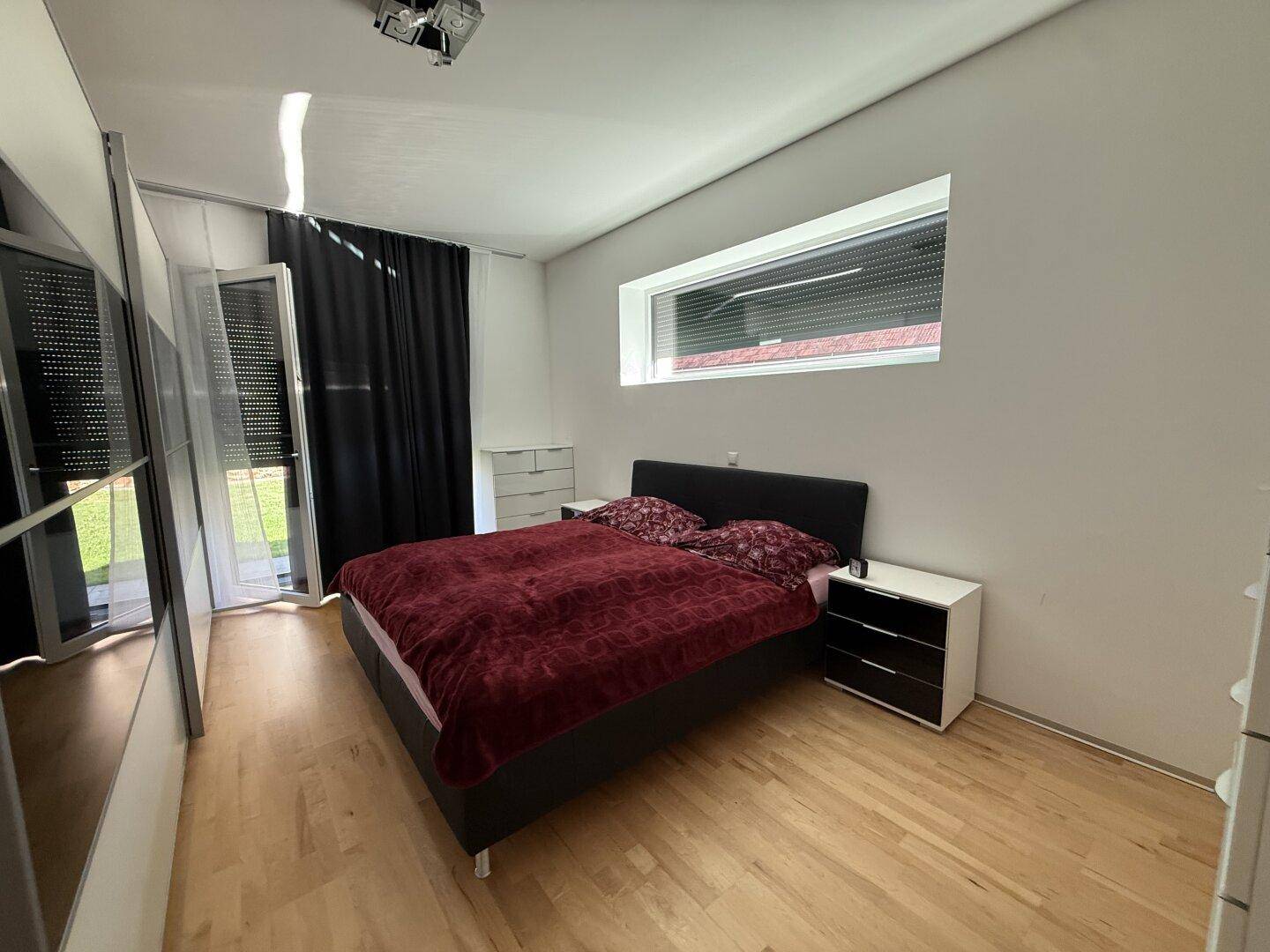 Schlafzimmer mit Doppelbett, Holzboden und Zugang zu einem Außenbereich.