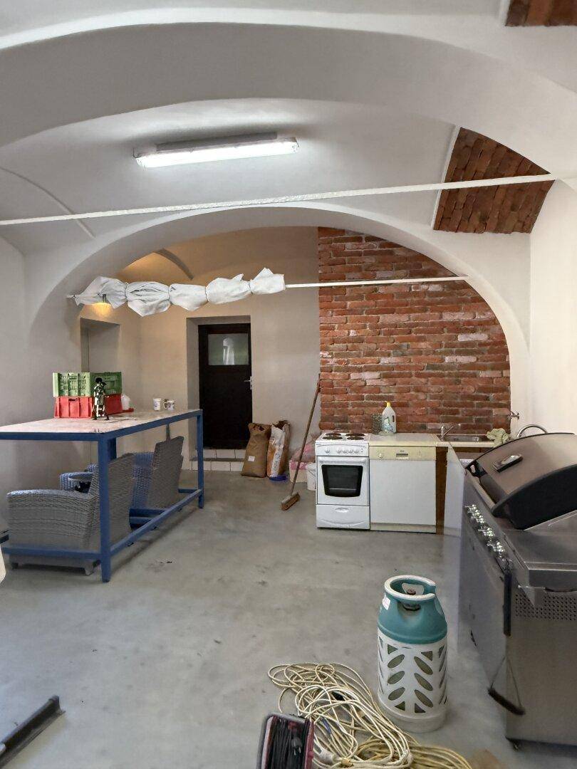 Großer Raum mit Gewölbedecke, unverputzten Ziegelwänden und Betonboden, als Werkstatt genutzt.