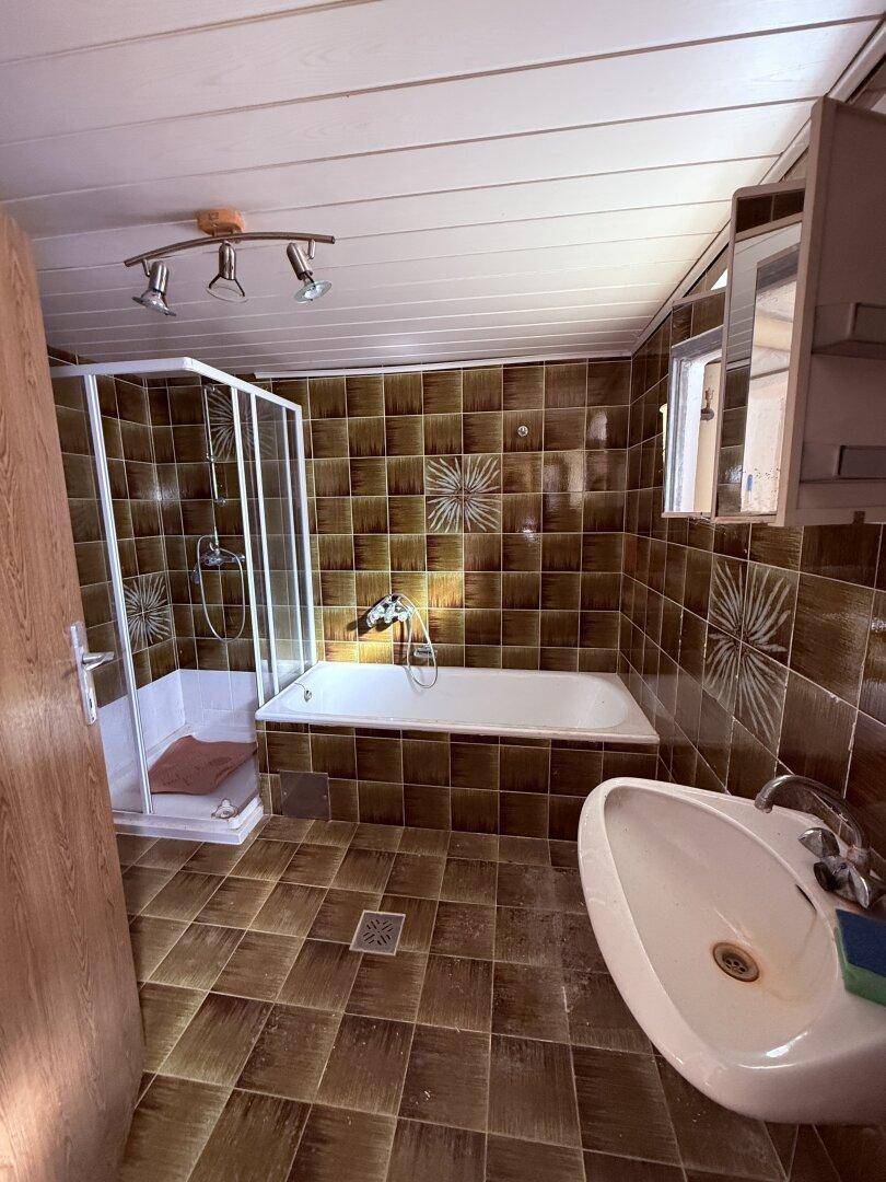 Badezimmer mit braunen Fliesen, Badewanne, Duschkabine und modernem Waschbecken.