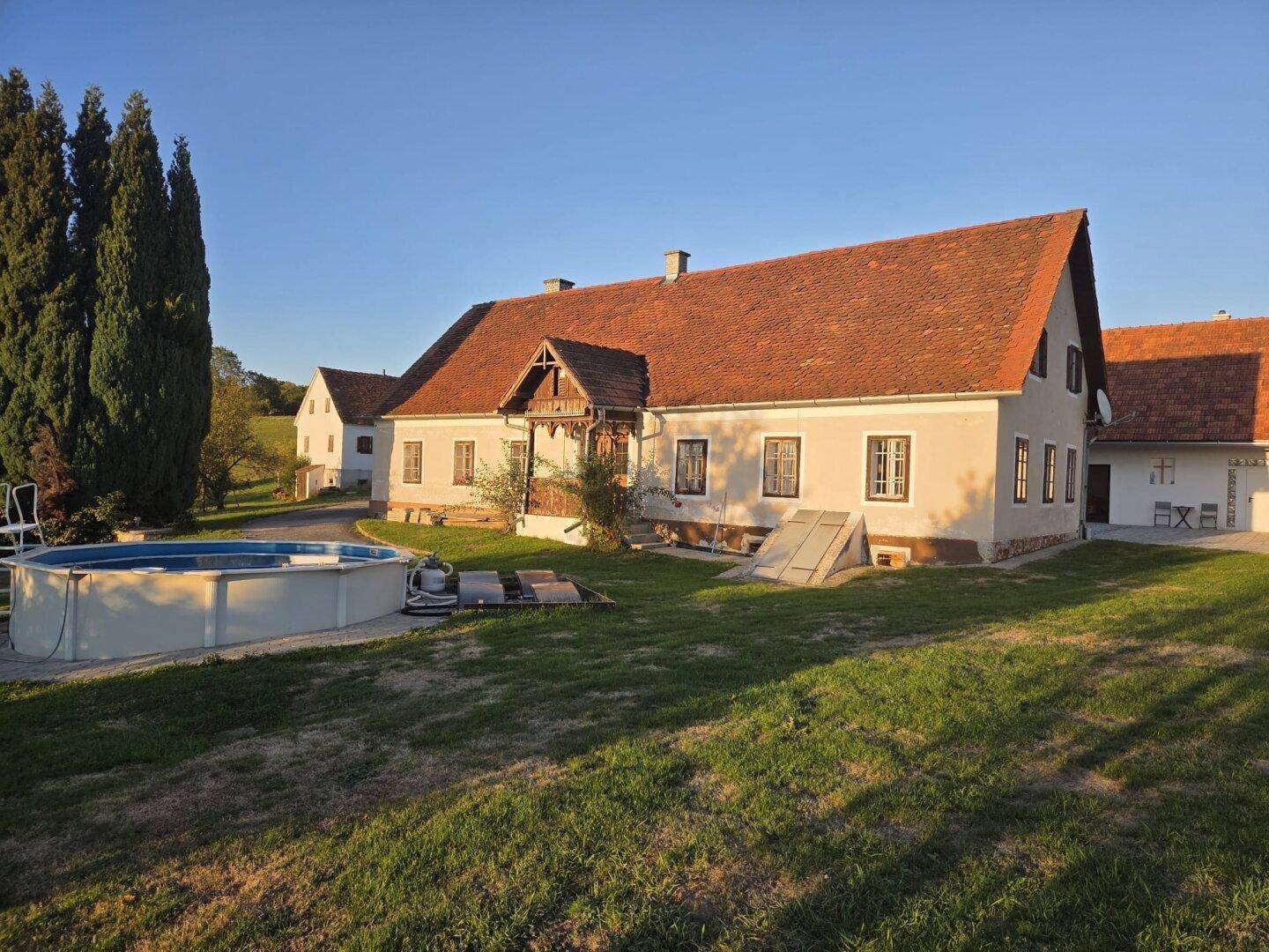 Traditionelles Landhaus mit Satteldach, umgeben von Grünflächen und einem Aufstellpool.