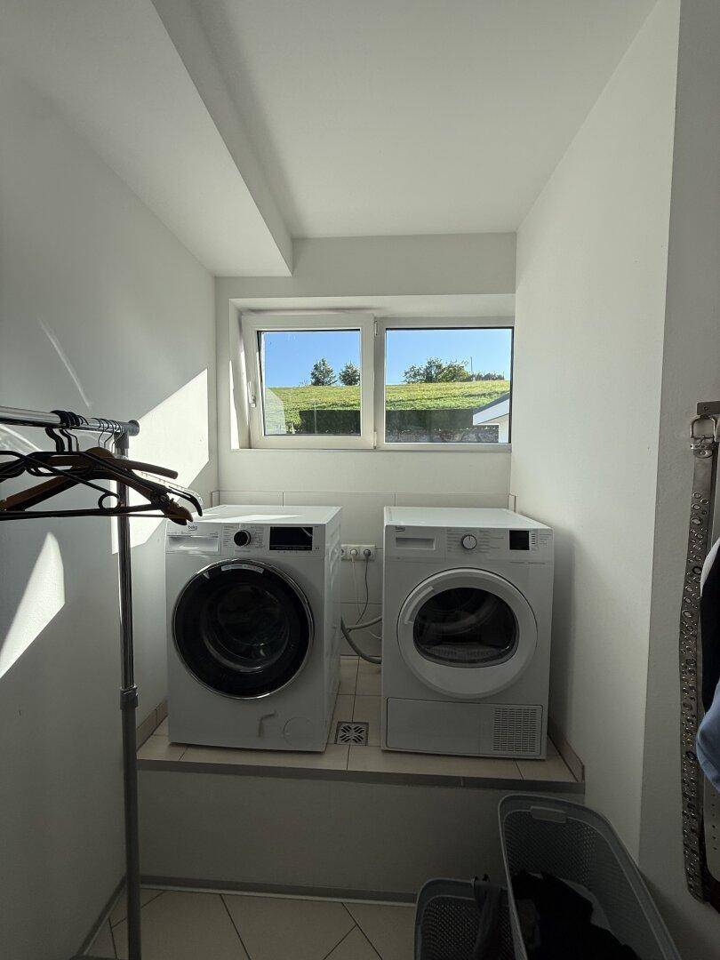 Praktischer Hauswirtschaftsraum mit Waschmaschine, Trockner und Fenster.