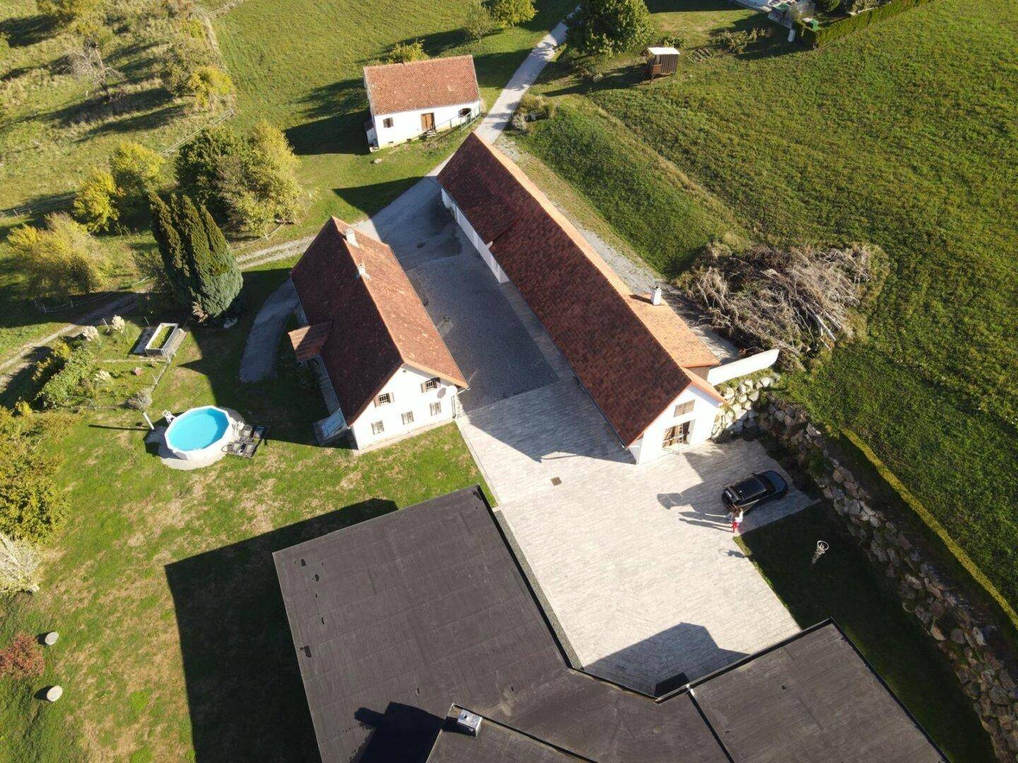 Luftaufnahme des Anwesens mit mehreren Gebäuden, weitläufigen Grünflächen und einem Pool.