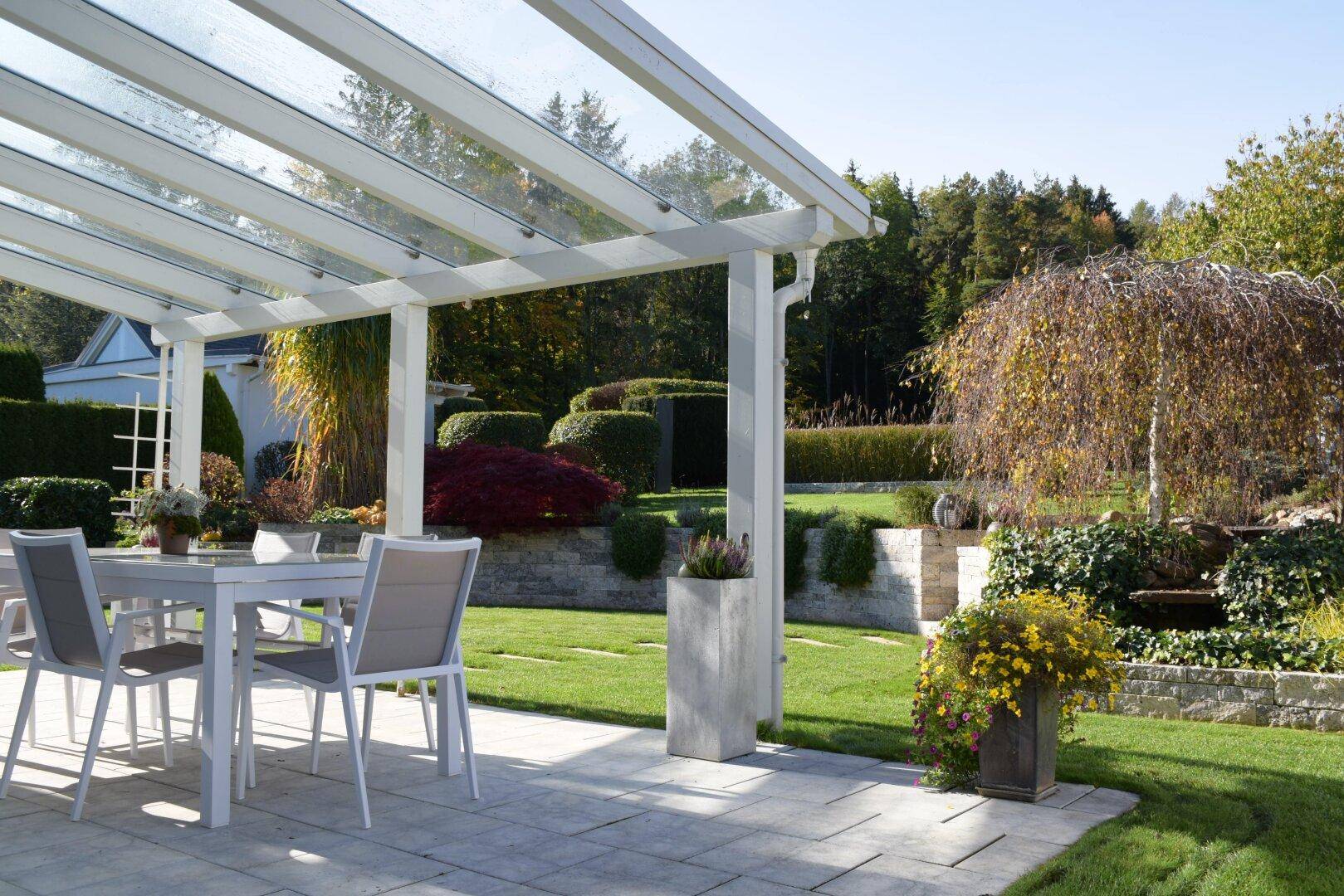 Überdachte Terrasse mit Gartenmöbeln und weitem Blick über die grüne Landschaft.