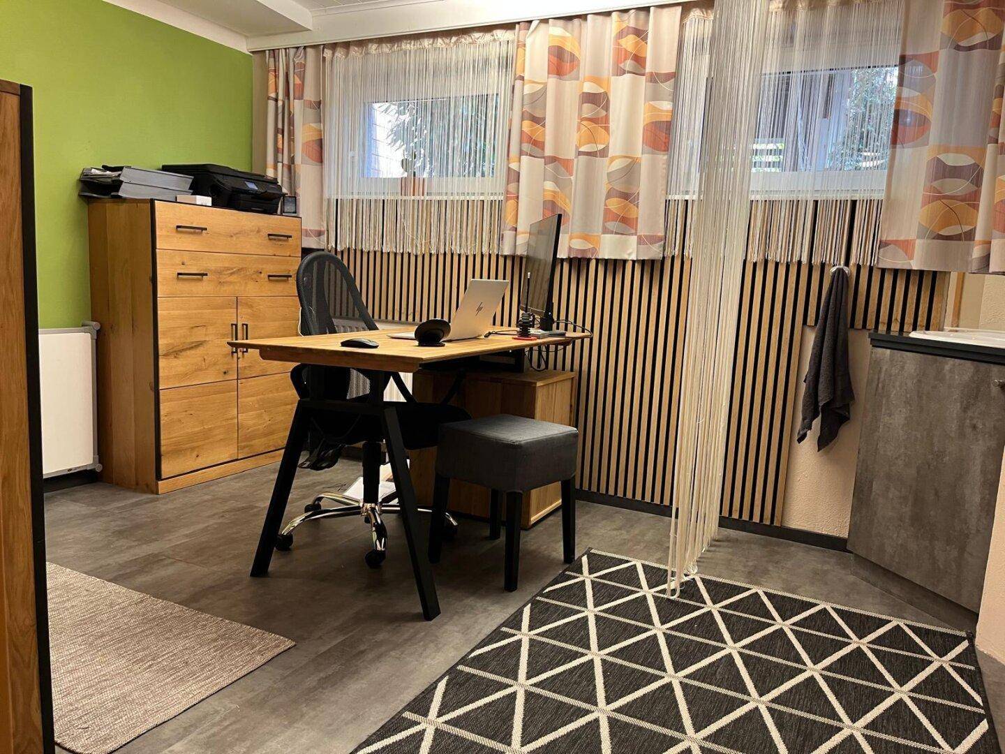Modernes Arbeitszimmer mit Schreibtisch, Holzmöbeln und dekorativer Wandverkleidung.