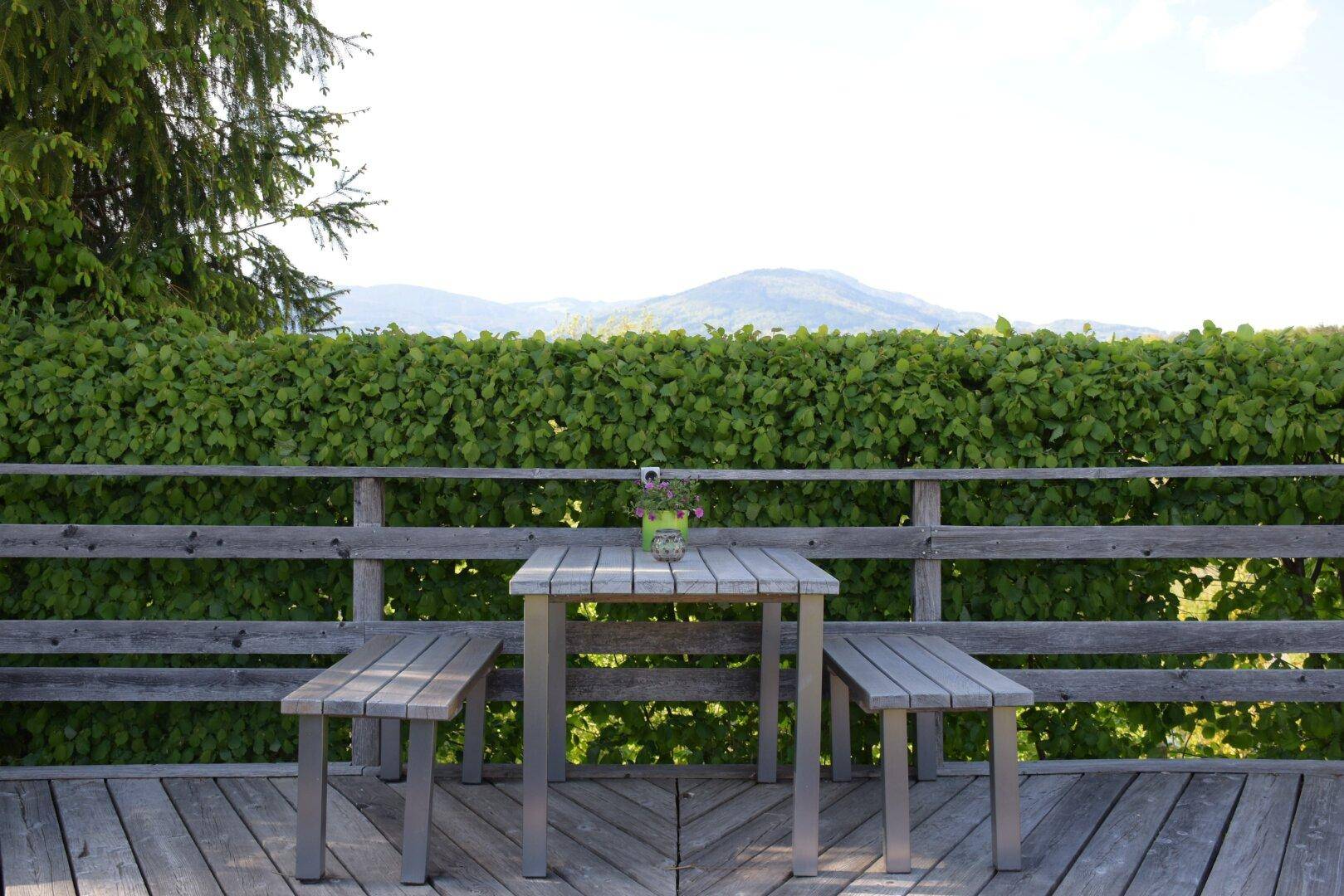 Holzterrasse mit Gartenmöbeln und weitem Blick über die grüne Landschaft.
