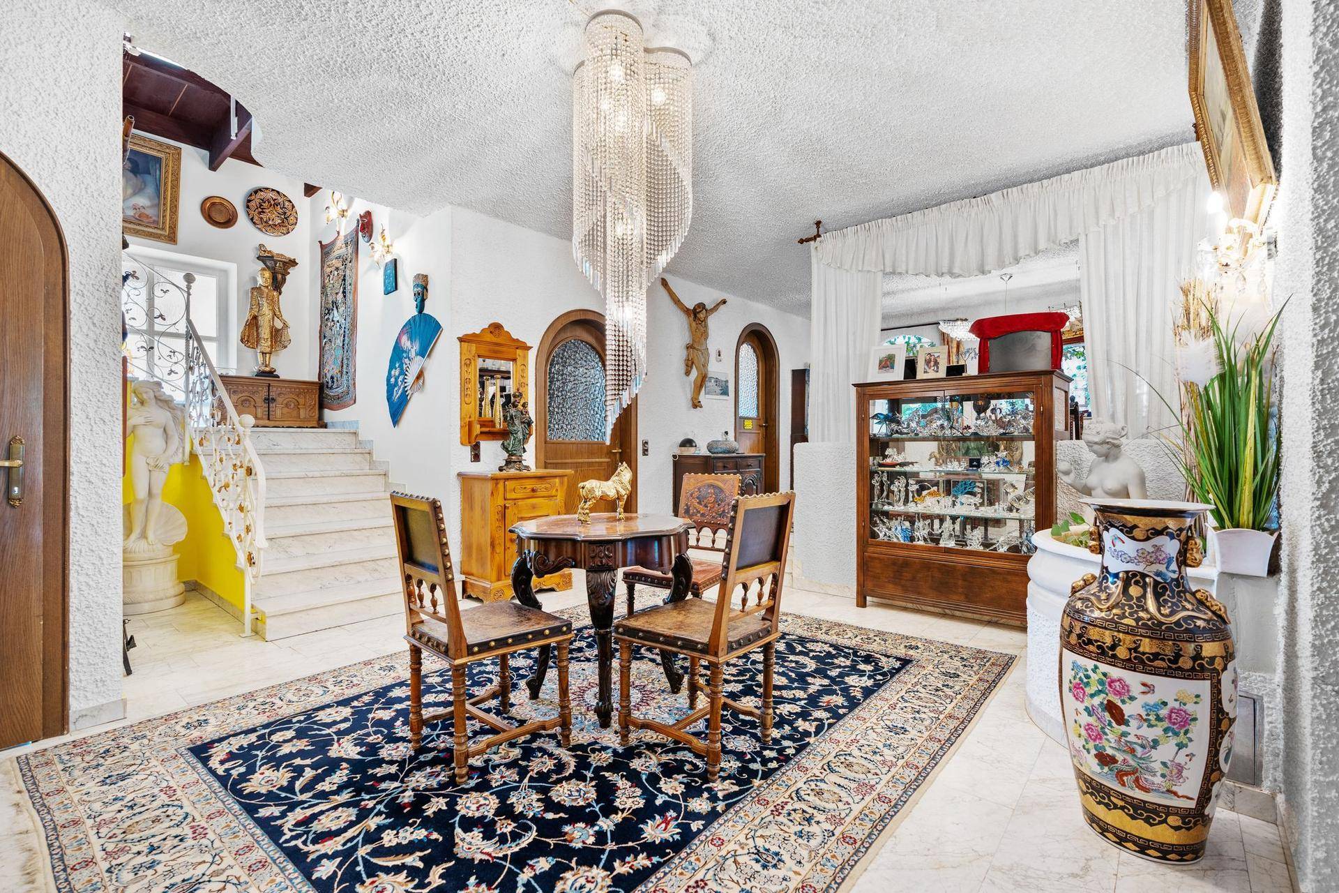 Repräsentativer Eingangsbereich mit Marmorboden, eleganter Treppe und kunstvollen Dekorationen.