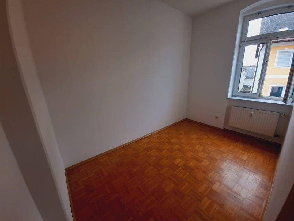Kleineres Zimmer mit Parkettboden und einem Fenster, ideal als Schlaf- oder Arbeitszimmer.