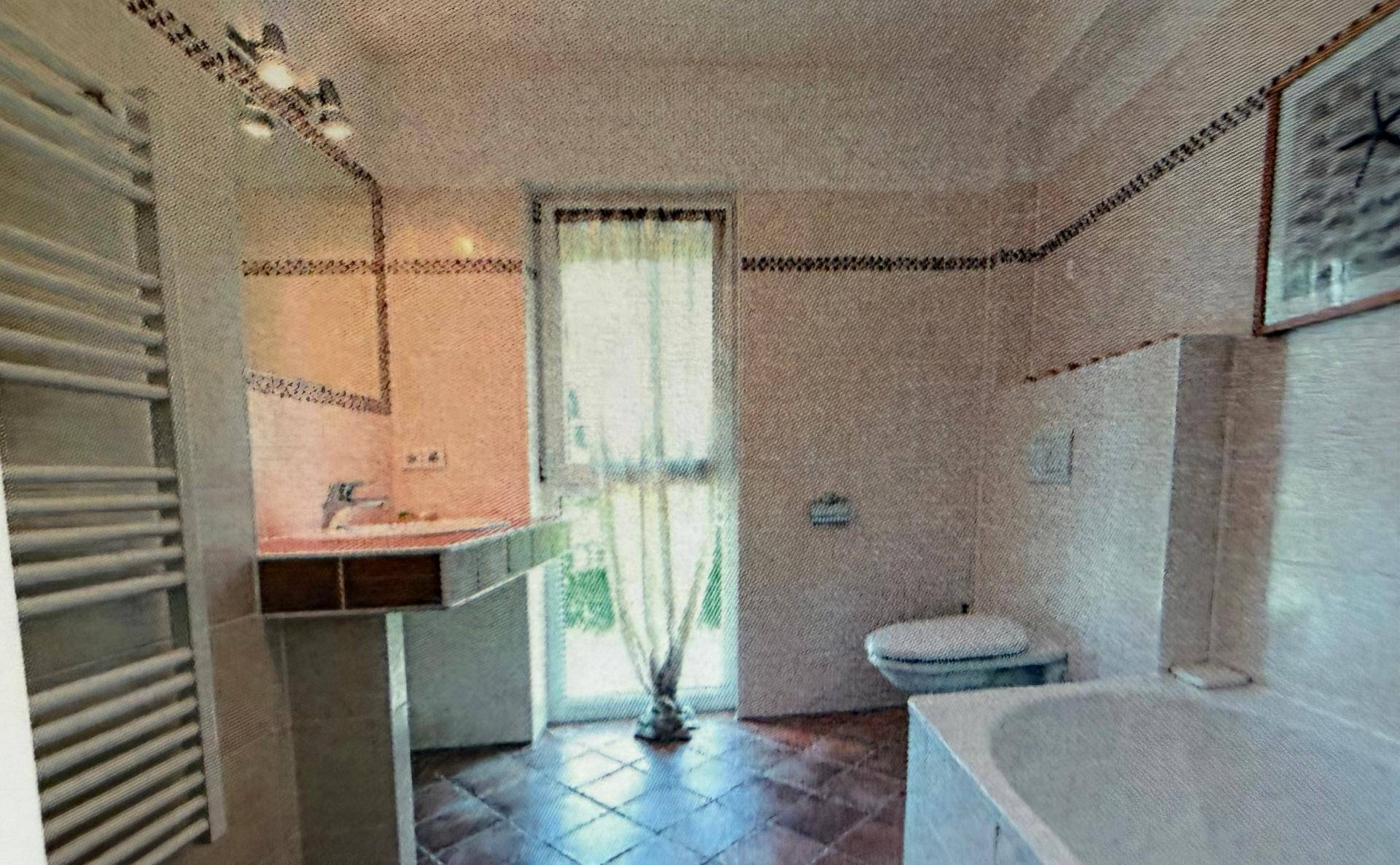 Badezimmer im Stil der 80er Jahre mit Badewanne, Waschbecken und Fenster.