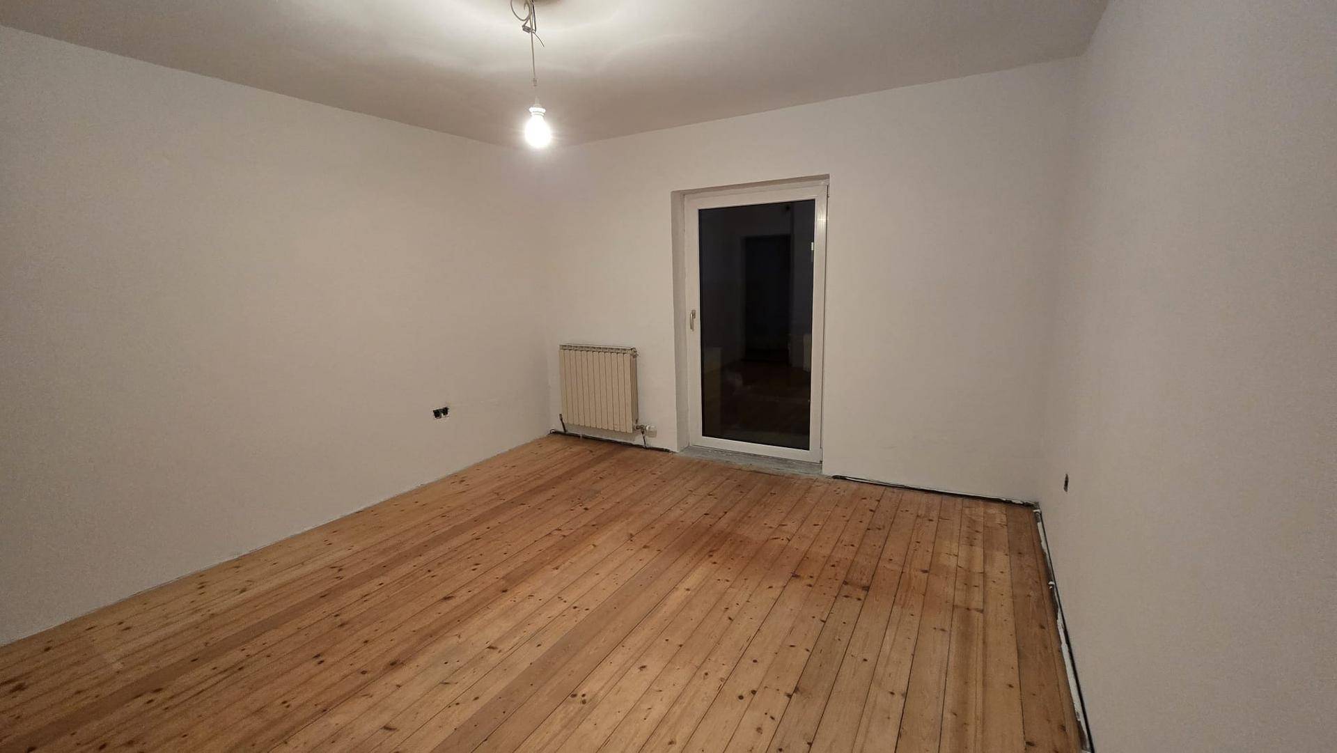 Leeres Zimmer mit hellem Holzplankenboden und weiß gestrichenen Wänden, bereit zur Einrichtung.
