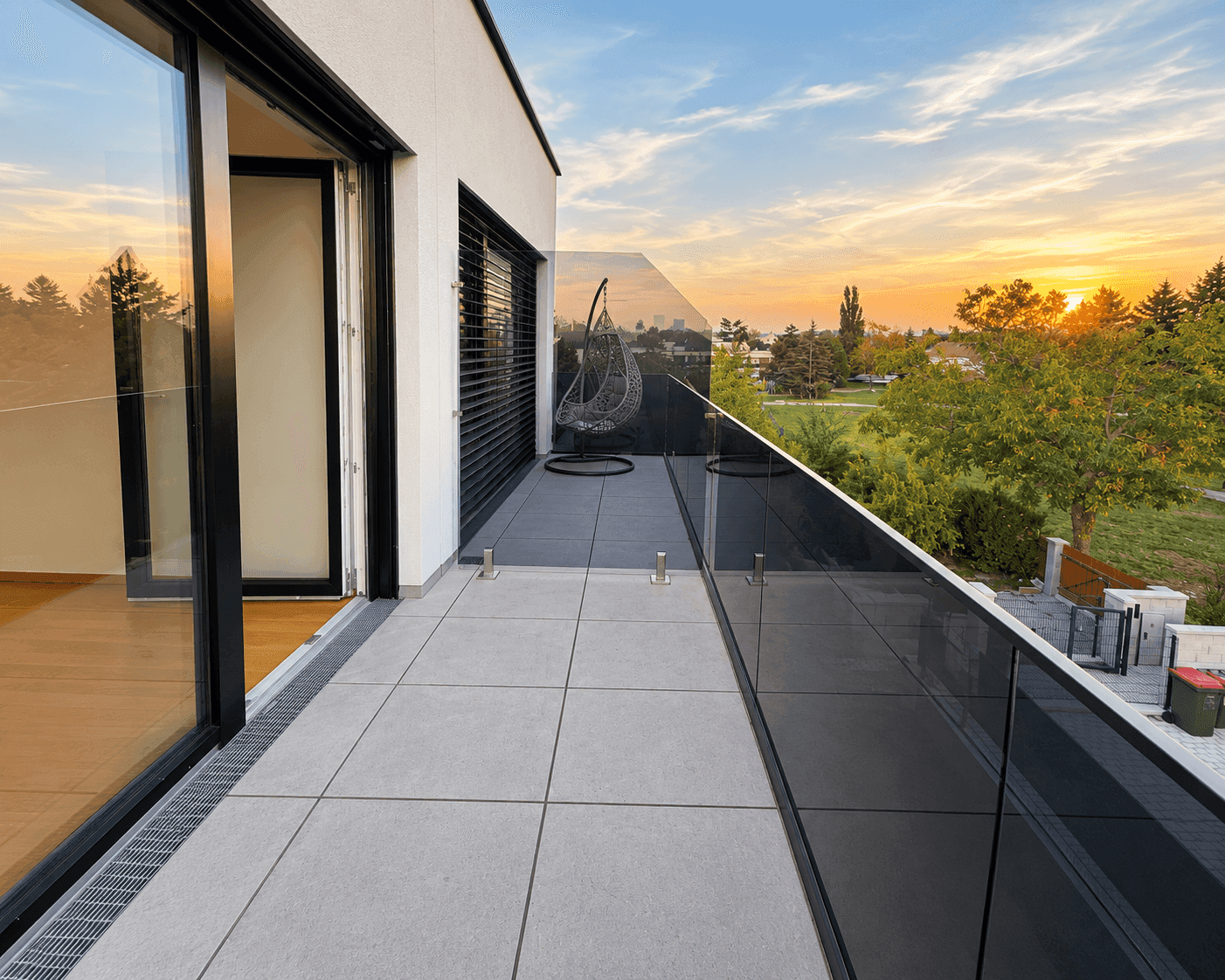 Moderner Balkon mit Glasgeländer und Hängesessel, ideal für entspannte Stunden.