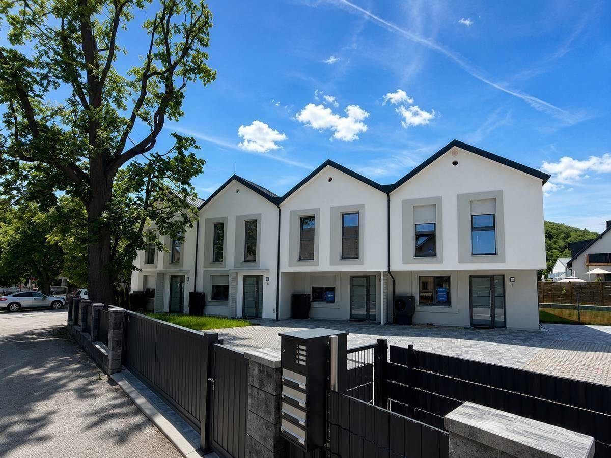 Reihe moderner Reihenhäuser mit gepflastertem Vorplatz und klarem Himmel.