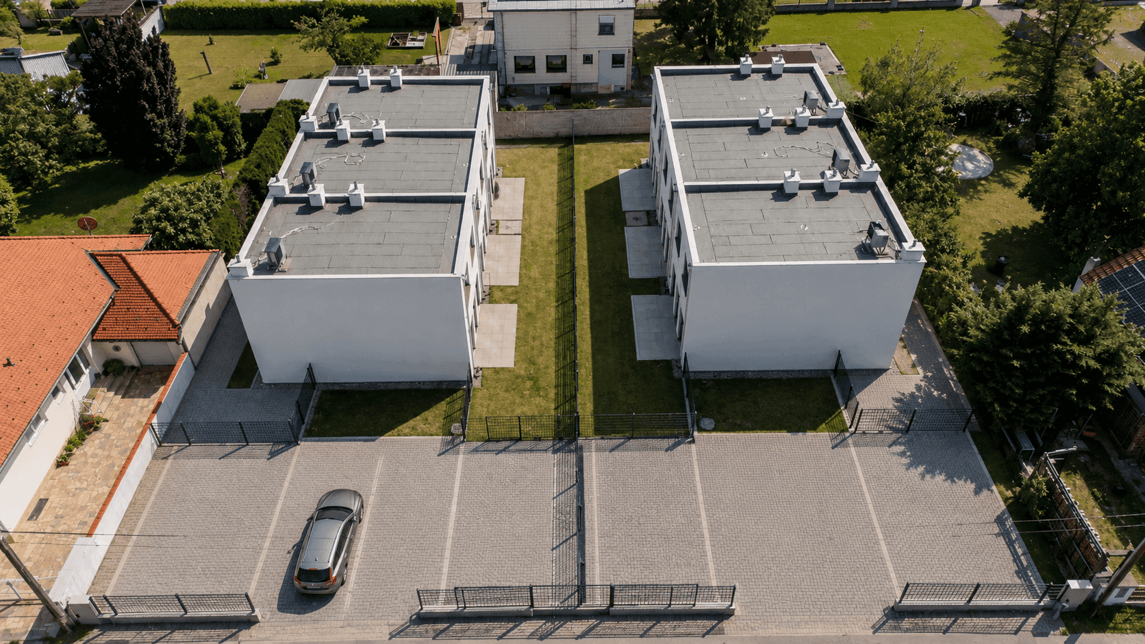 Luftaufnahme von zwei modernen Gebäuden mit Flachdächern und Parkplätzen.