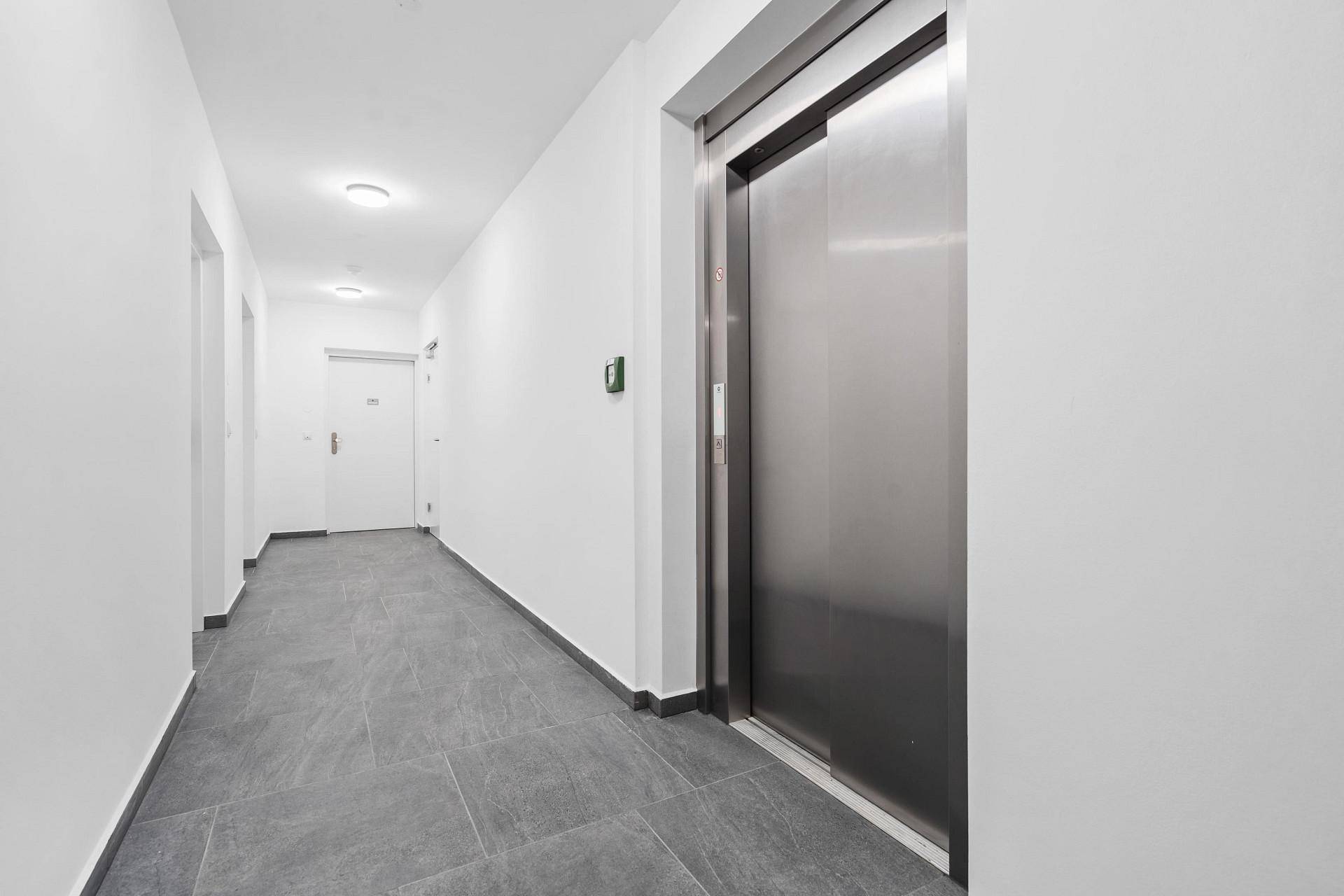 Heller Flur im Gemeinschaftsbereich mit Fliesenboden und modernem Aufzug.