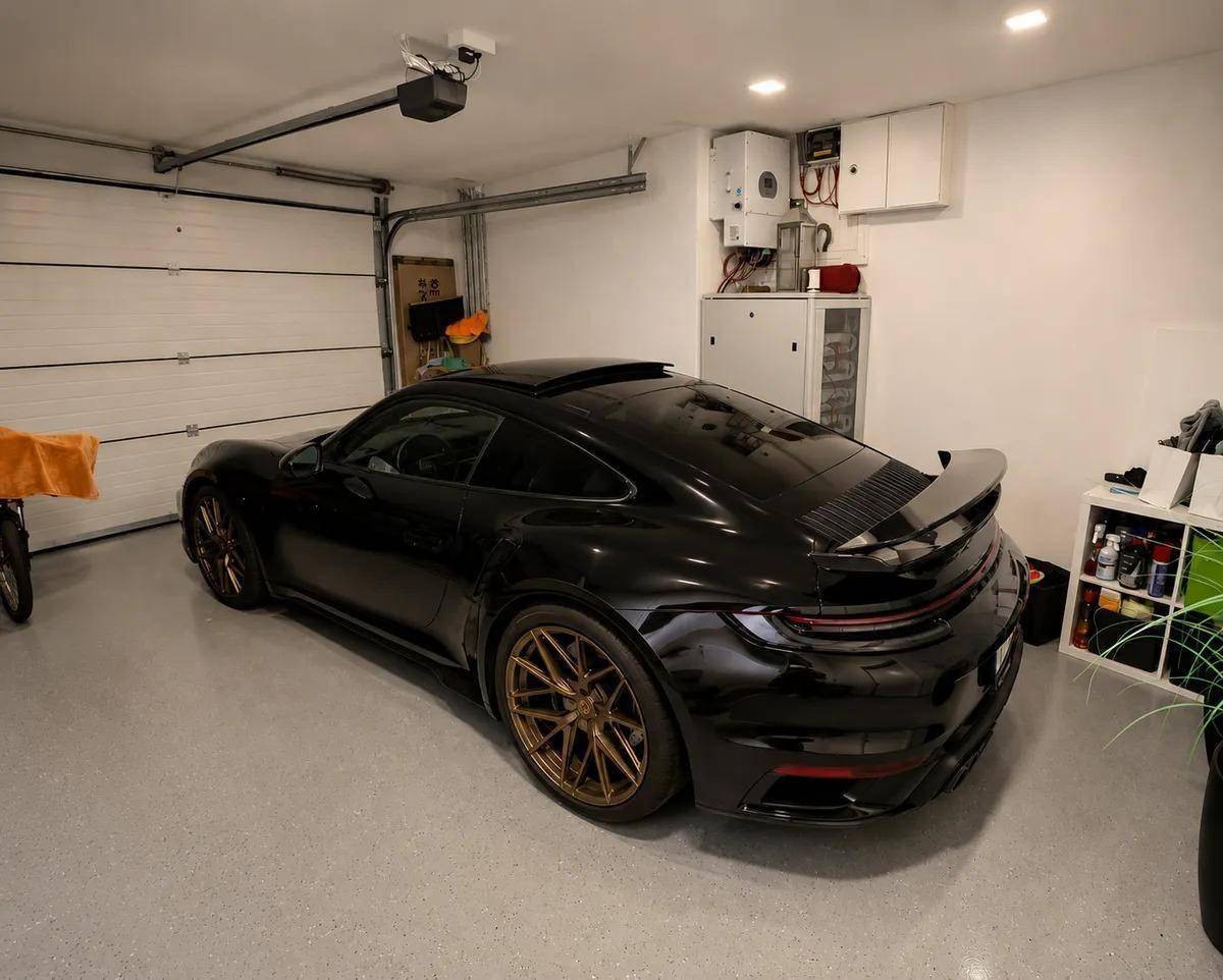 Geräumige und saubere Garage mit glänzendem Boden und einem geparkten Sportwagen.