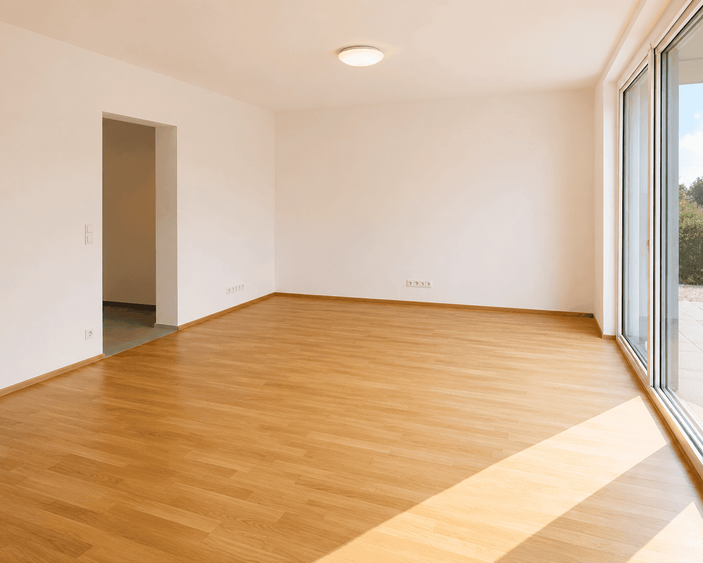 Geräumiges, helles Zimmer mit Holzboden und großen Fenstern mit Zugang nach draußen.