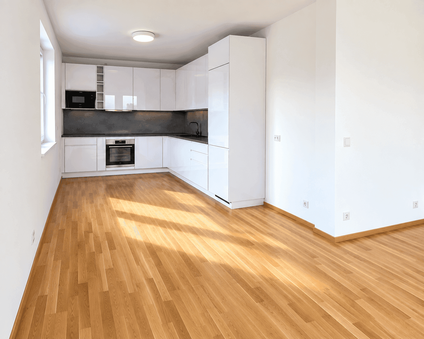 Moderne Einbauküche mit weißen Hochglanzfronten und dunkler Arbeitsplatte im offenen Wohnbereich.