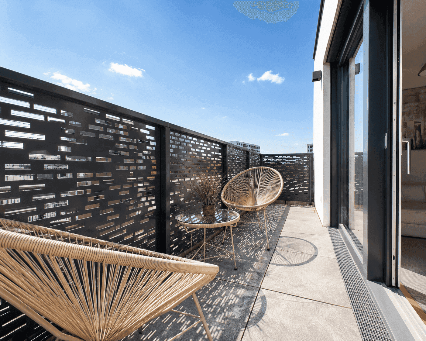 Gemütlicher Balkon mit Sitzgelegenheiten und Blick auf die Umgebung unter blauem Himmel.