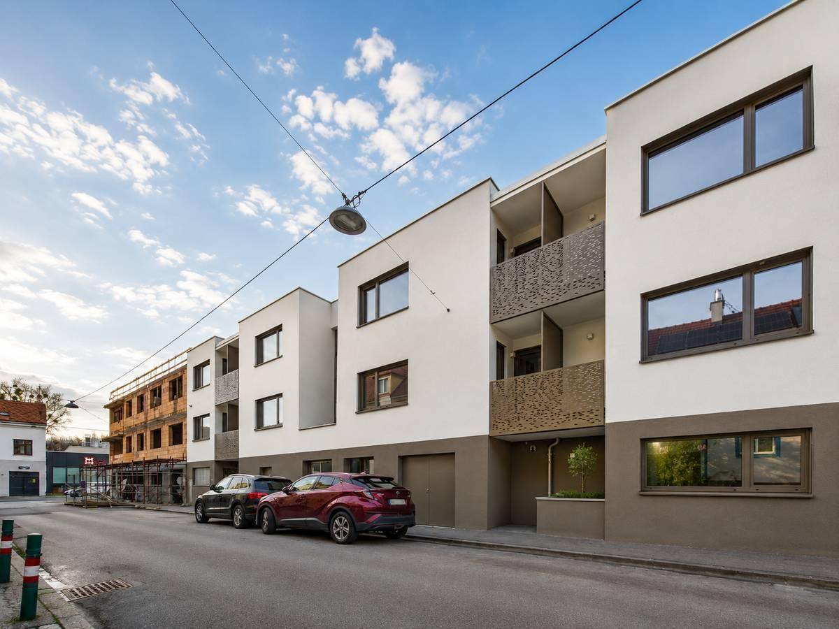 Moderne Wohngebäude mit Balkonen und großen Fenstern entlang einer ruhigen Straße.