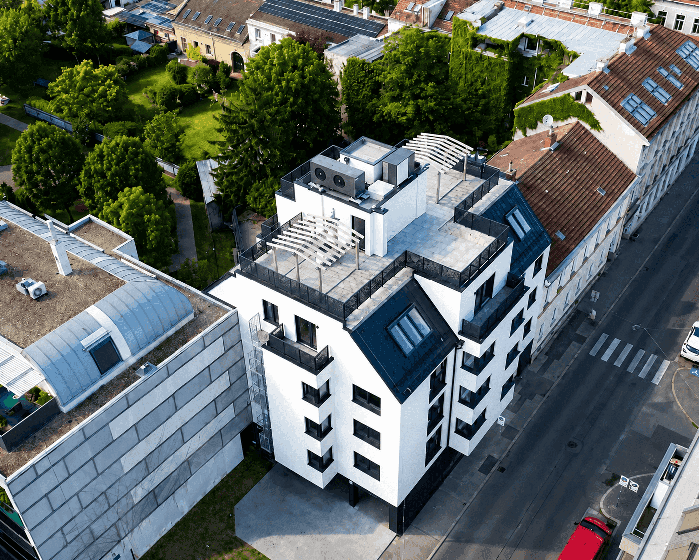 Luftaufnahme eines modernen Wohngebäudes mit Dachterrassen in städtischer Umgebung.