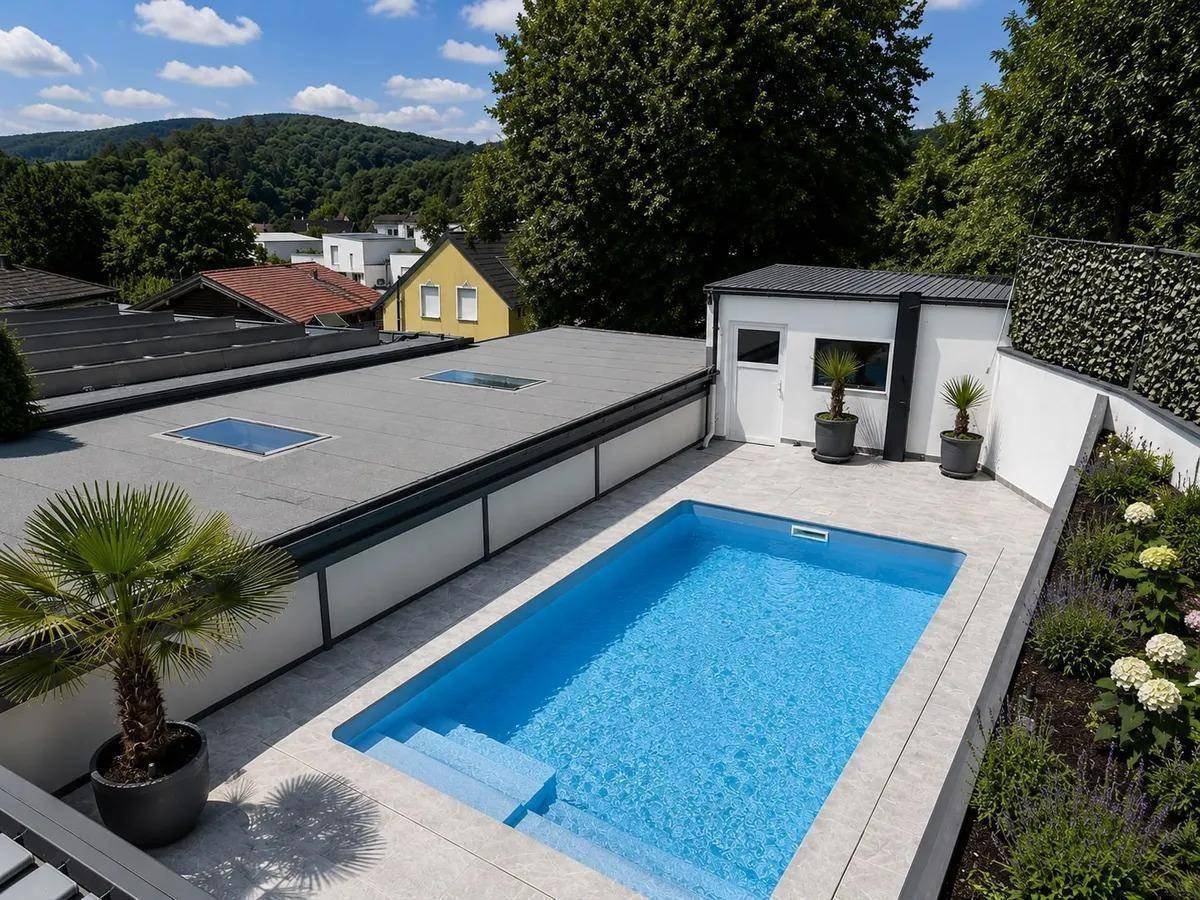 Außenbereich mit rechteckigem Pool, Liegeflächen und Blick auf die Umgebung.
