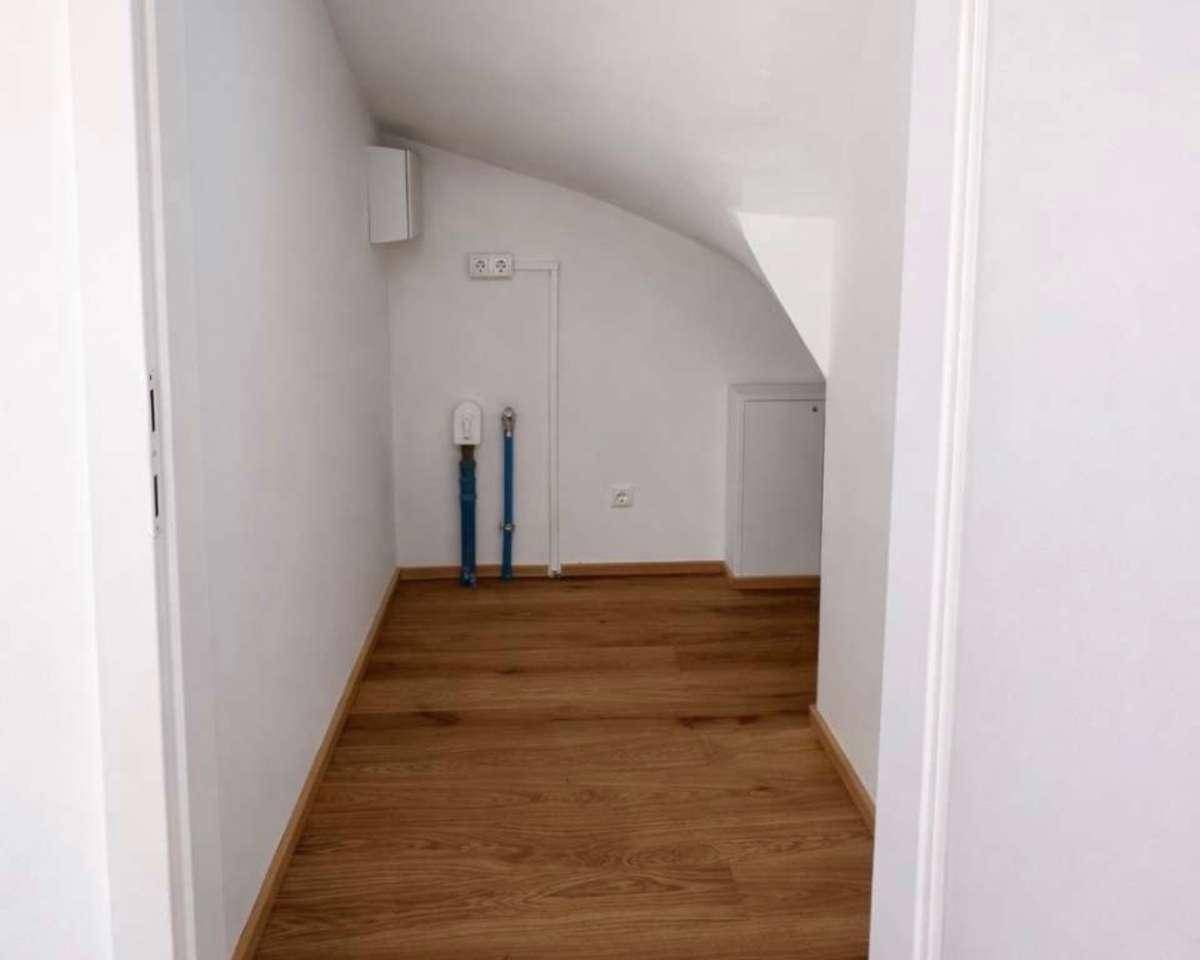 Praktischer Abstellraum im Dachgeschoss mit Anschlüssen und Holzboden.