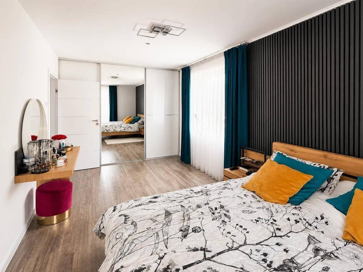 Modernes Schlafzimmer mit Laminatboden, Spiegelschränken und farbigen Akzenten.
