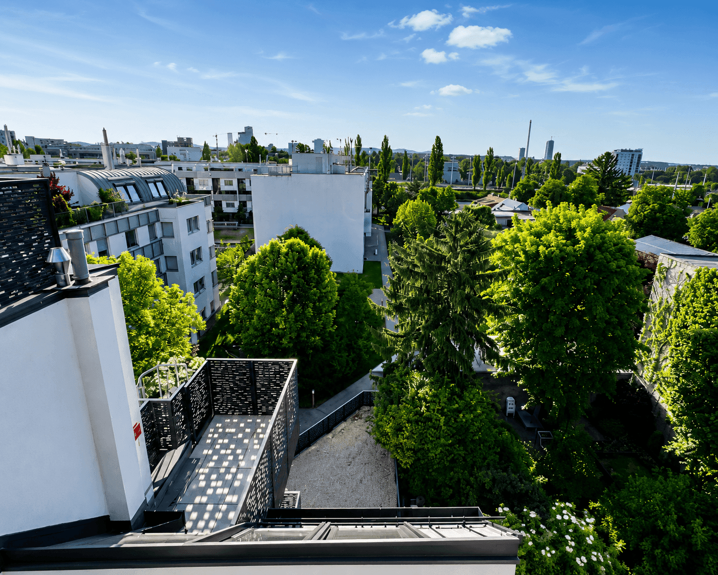 Weitläufiger Blick über die Stadt mit viel Grün und blauem Himmel.