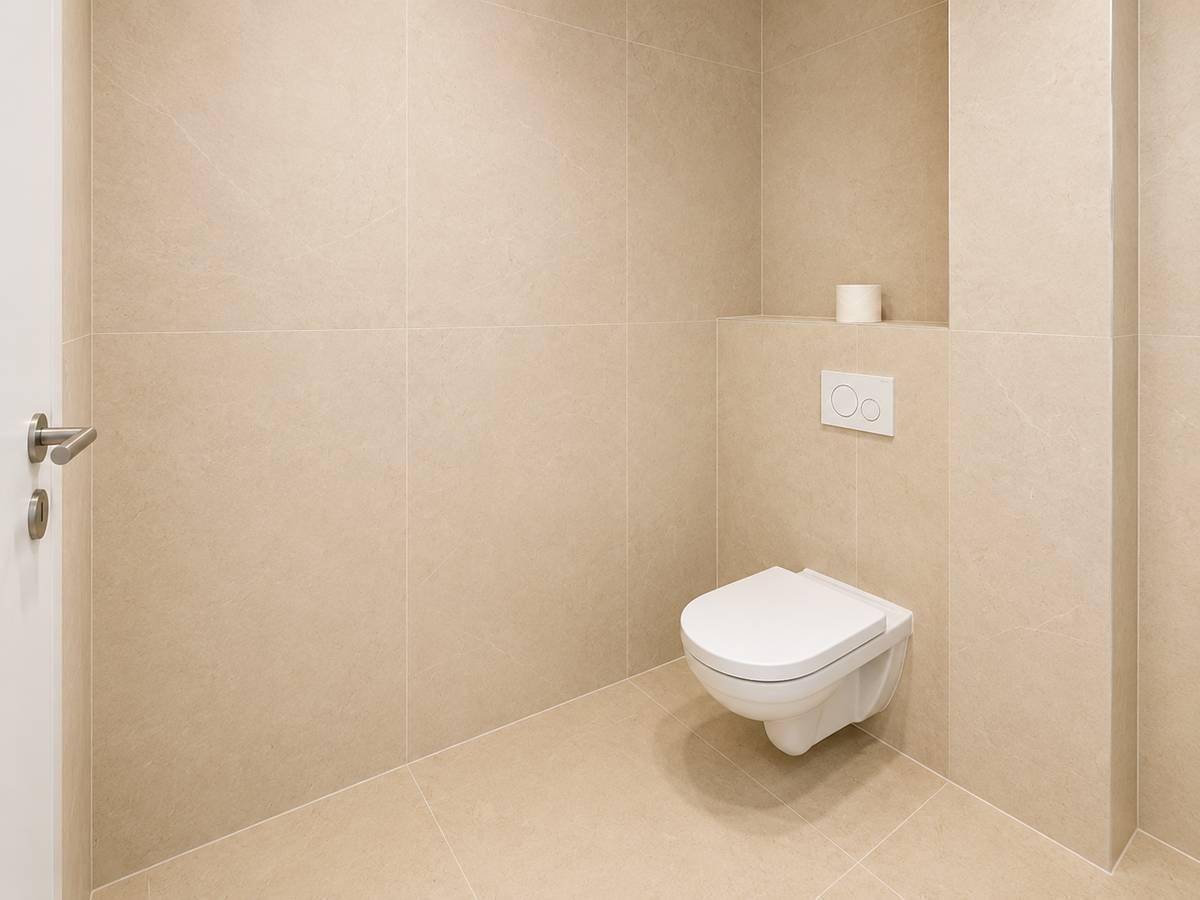 Modernes wandhängendes WC in einem hell gefliesten Raum mit minimalistischem Design.