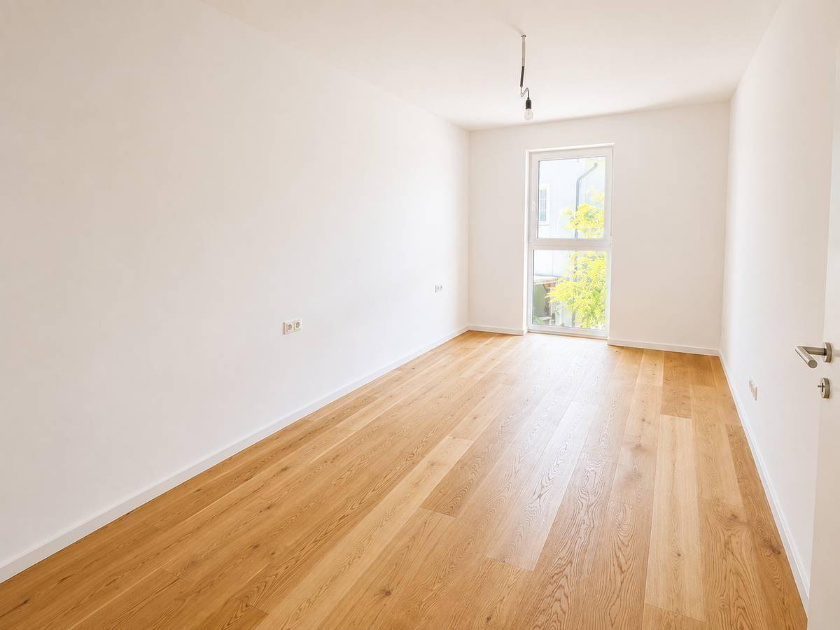 Helles Zimmer mit Parkettboden und großem Fenster, ideal als Schlaf- oder Kinderzimmer.