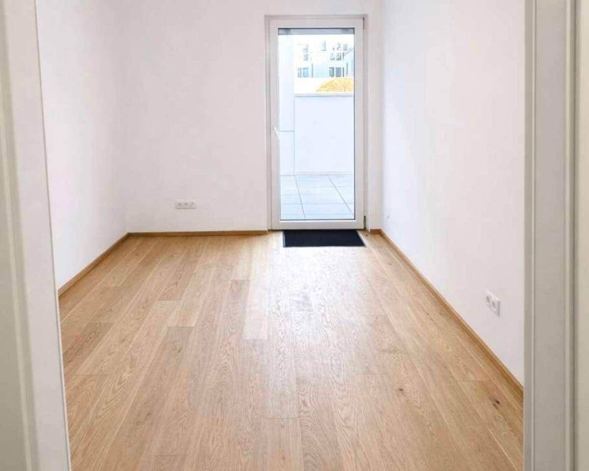 Heller Raum mit Holzboden und direktem Zugang zu einem Außenbereich.