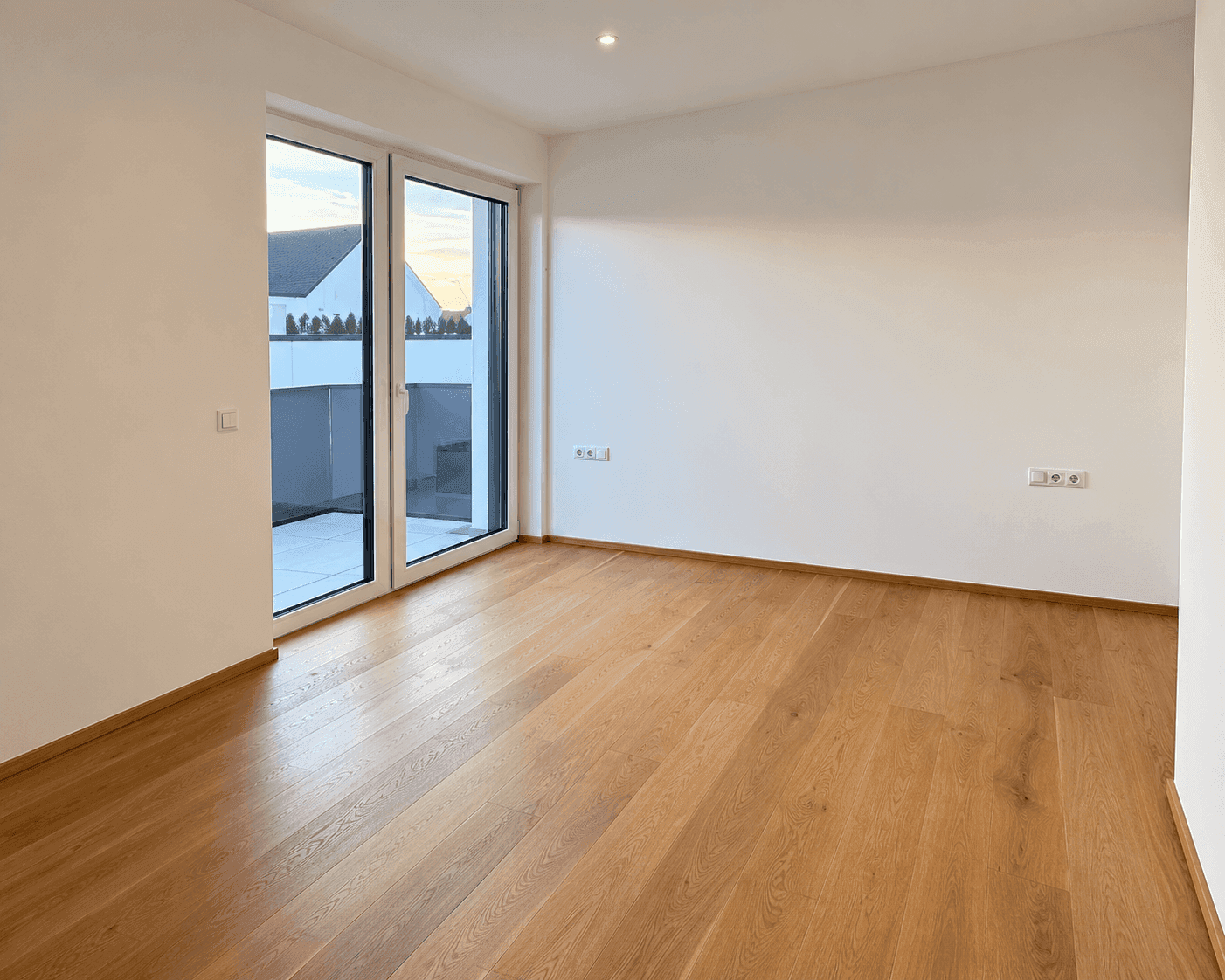 Helles Zimmer mit Eichenparkett und Zugang zu einem sonnigen Balkon.