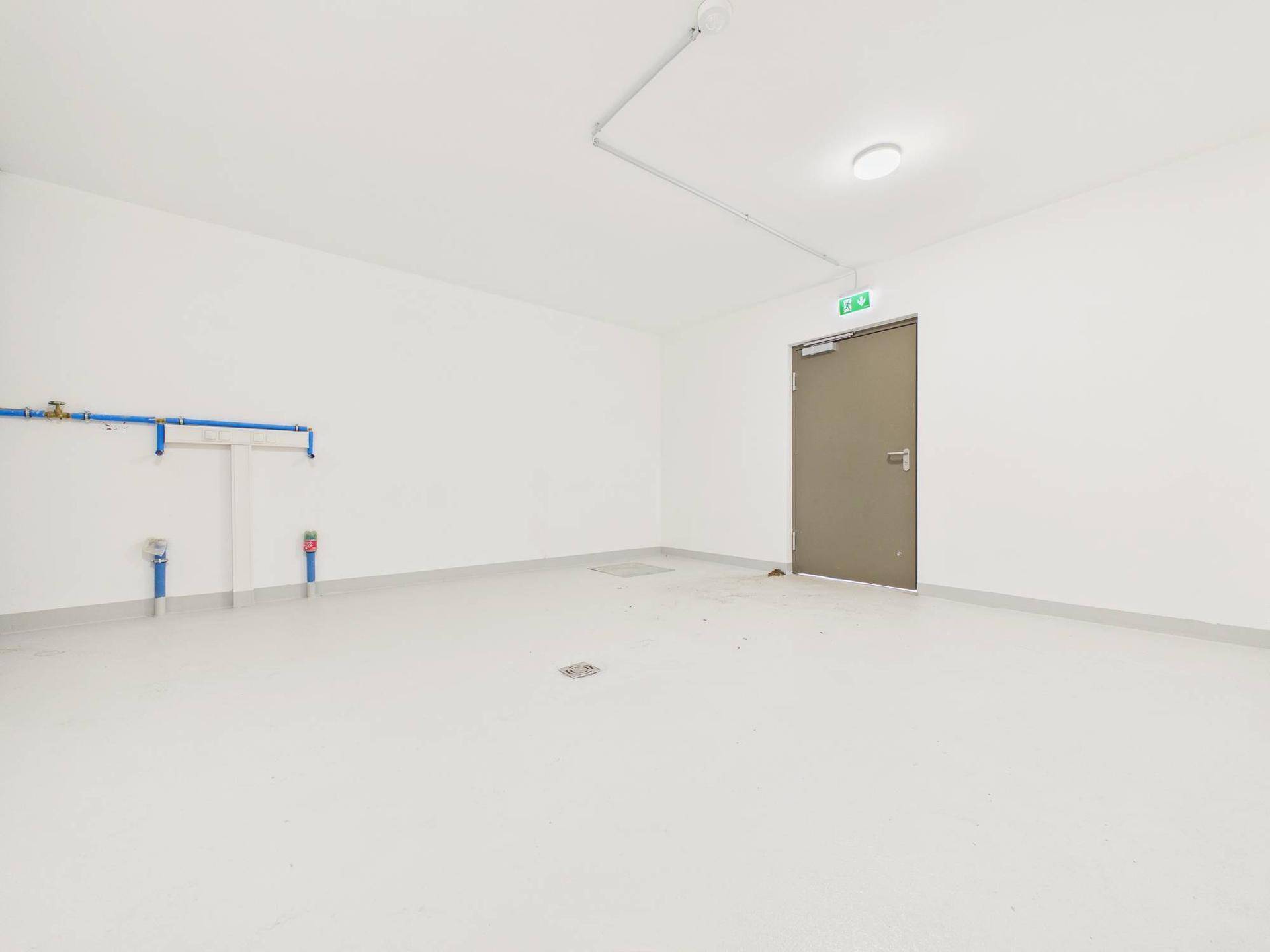 Geräumiger Abstellraum mit weißem Boden und sichtbaren Installationen, ideal für Lagerung.