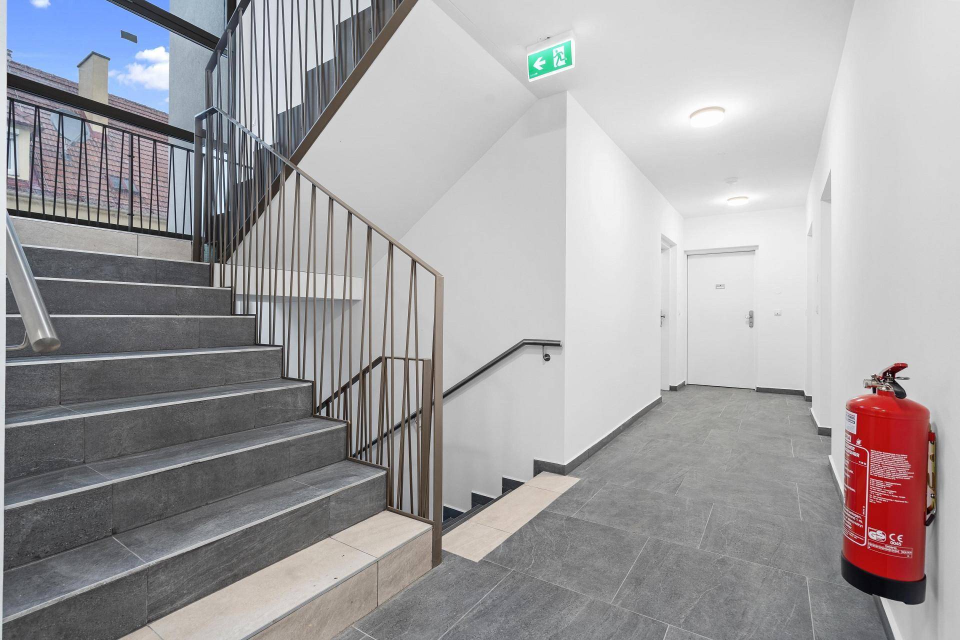 Treppenhaus und Flur im Gemeinschaftsbereich mit Fliesenboden und Brandschutzvorrichtung.
