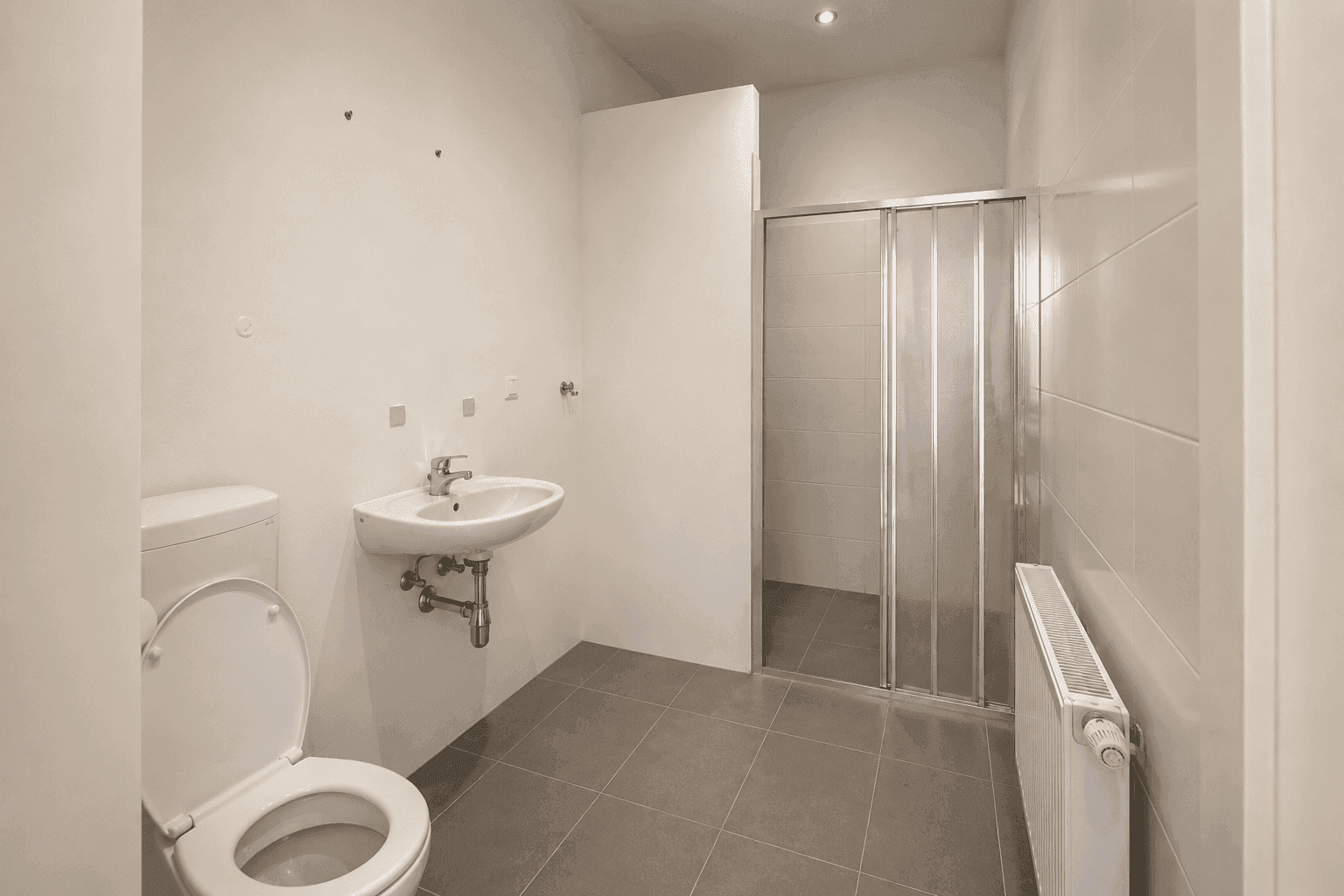Modernes Badezimmer mit Dusche, WC und Waschbecken in neutralen Farbtönen.