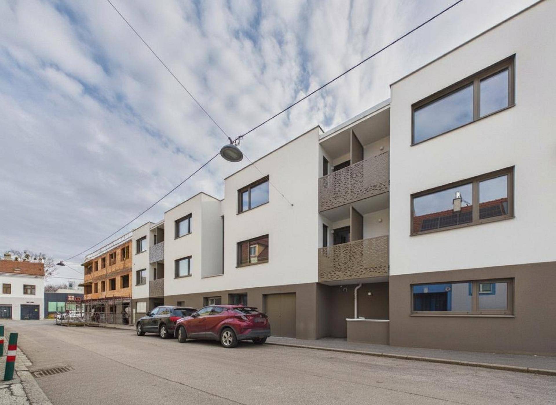 Neubau-Fassade mit modernen Fenstern und Balkonen entlang einer ruhigen Wohnstraße.