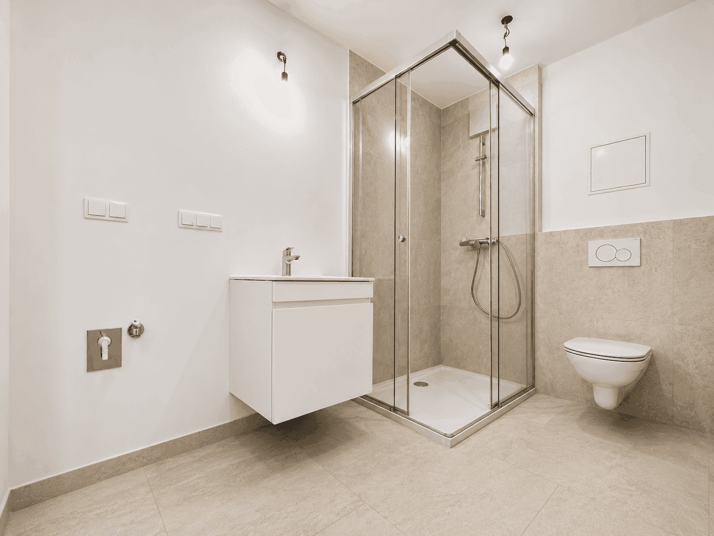 Modernes Badezimmer mit Duschkabine, Waschbecken und wandhängendem WC in hellen Farbtönen.