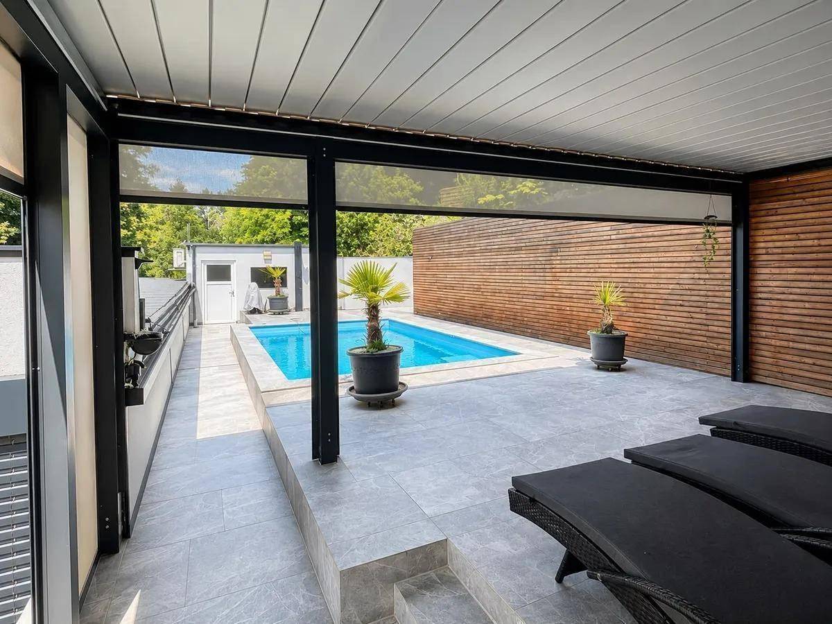 Überdachte Terrasse mit Lounge-Möbeln und Blick auf den privaten Swimmingpool.