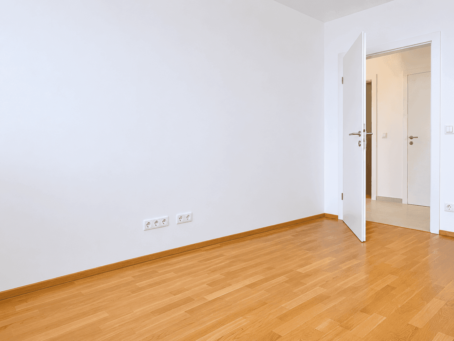 Helles Zimmer mit Holzboden und weiß gestrichenen Wänden, ideal für Schlaf- oder Arbeitszimmer.