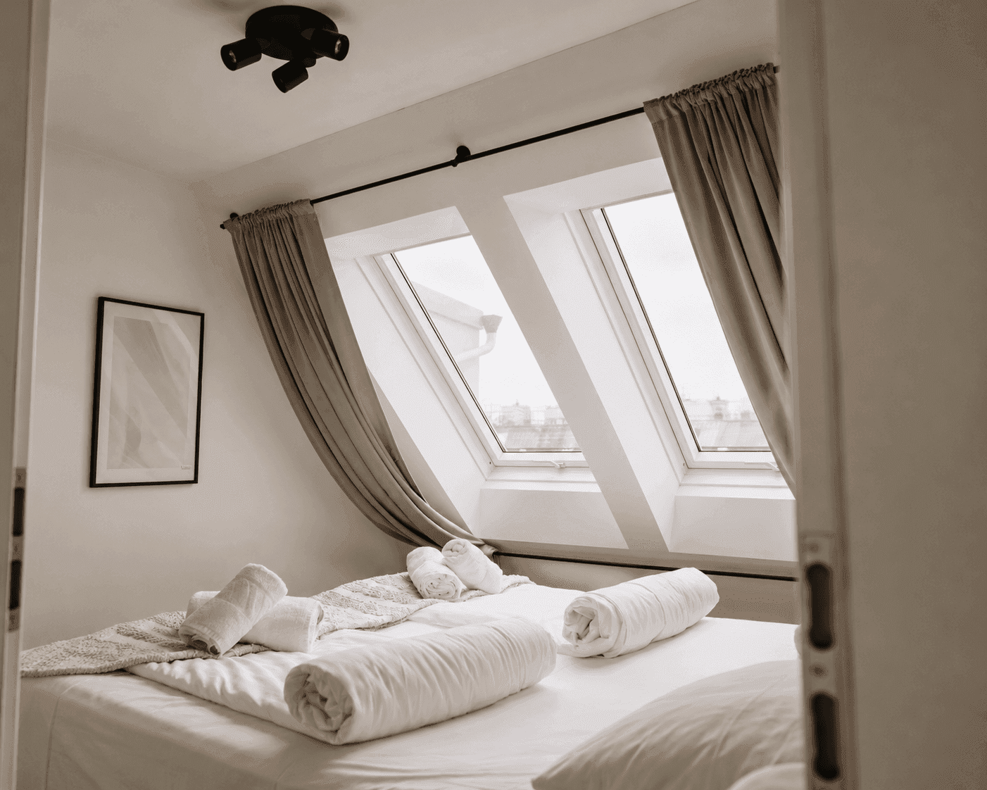 Helles Schlafzimmer mit zwei Dachfenstern, die viel Tageslicht hereinlassen und eine offene Atmosphäre schaffen.