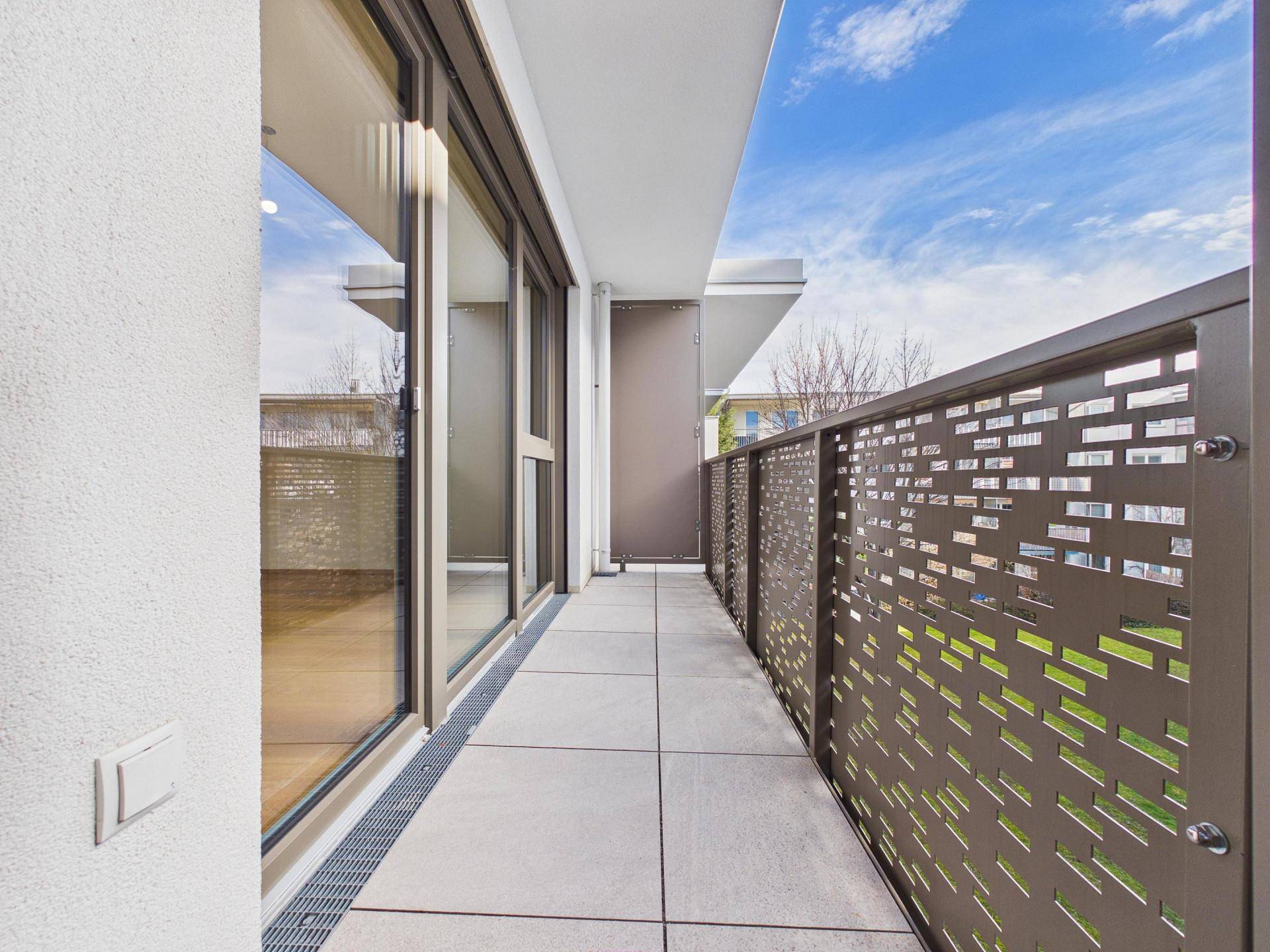 Langer Balkon mit modernen Metallgeländern und Fliesenboden, ideal für Entspannung.